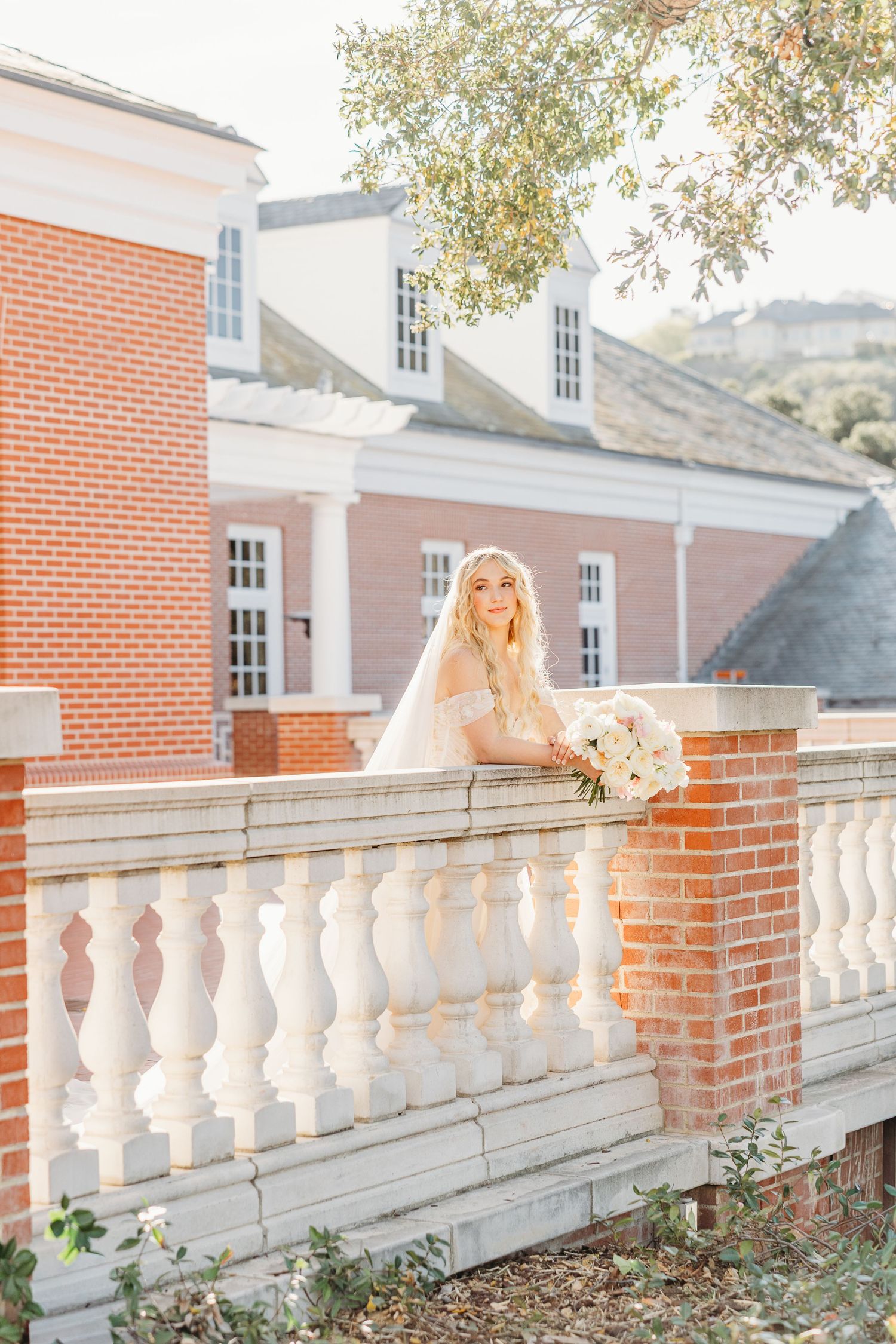 Sunlit veil flows gracefully along a classic white balustrade against red brick architecture.