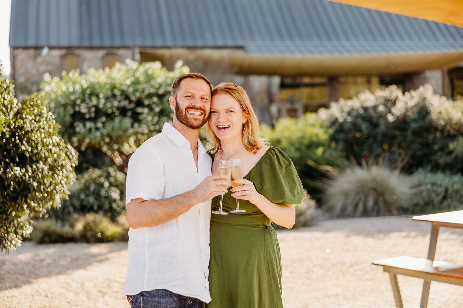 Couple enjoying a romantic outdoor moment together in warm sunlight near garden foliage.