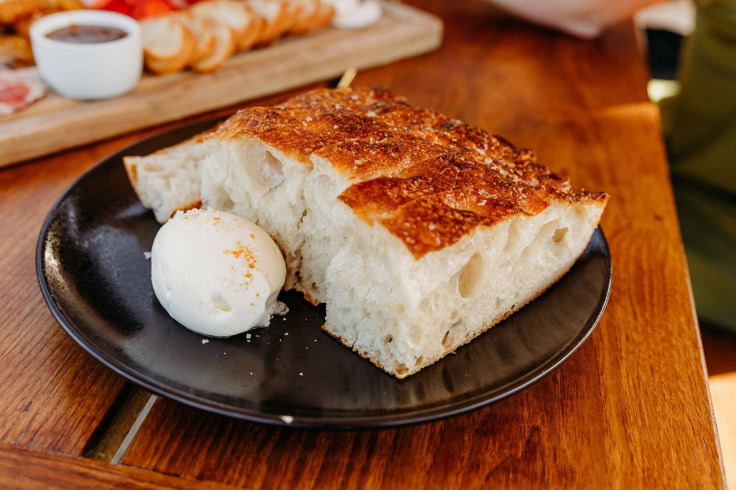 Fresh baked bread slices arranged on wooden cutting board with coffee cup.