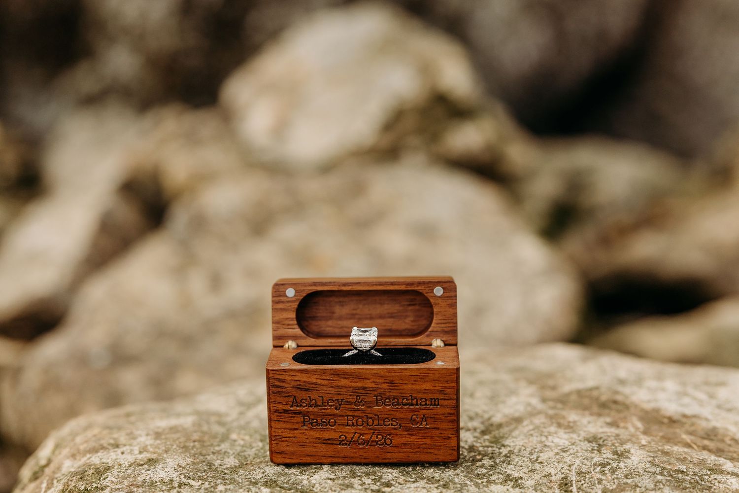 Small wooden box displayed on natural stone surface in outdoor setting.