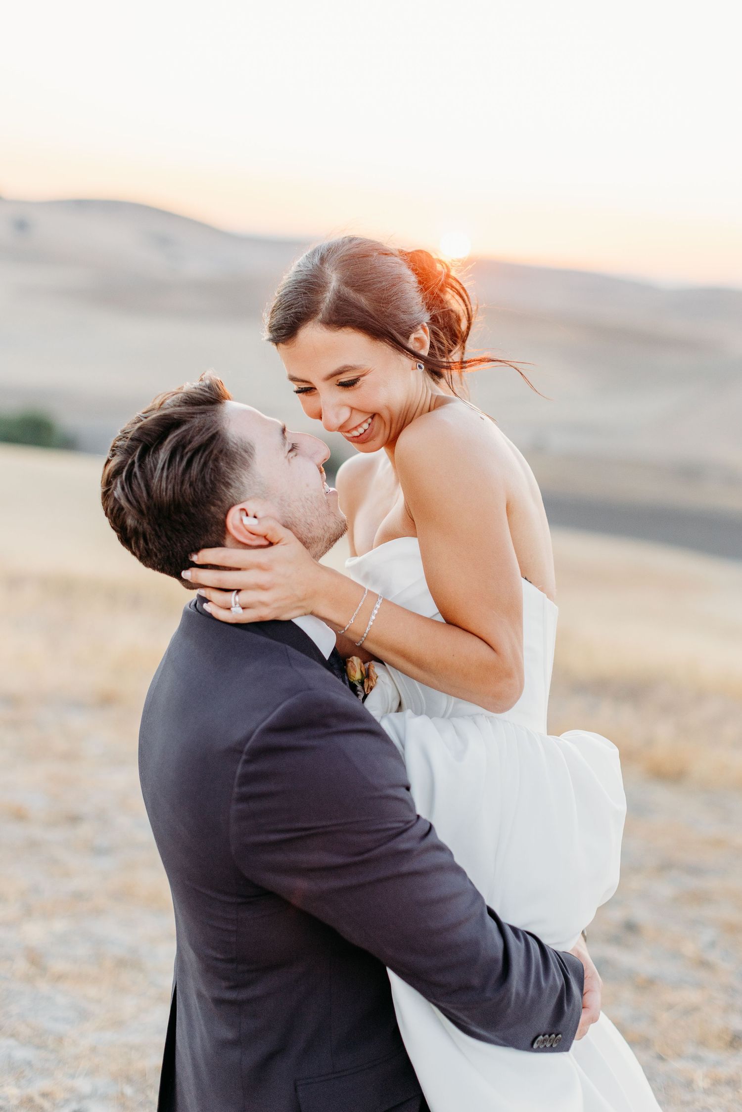 Intimate wedding moment captured during golden hour in natural landscape.