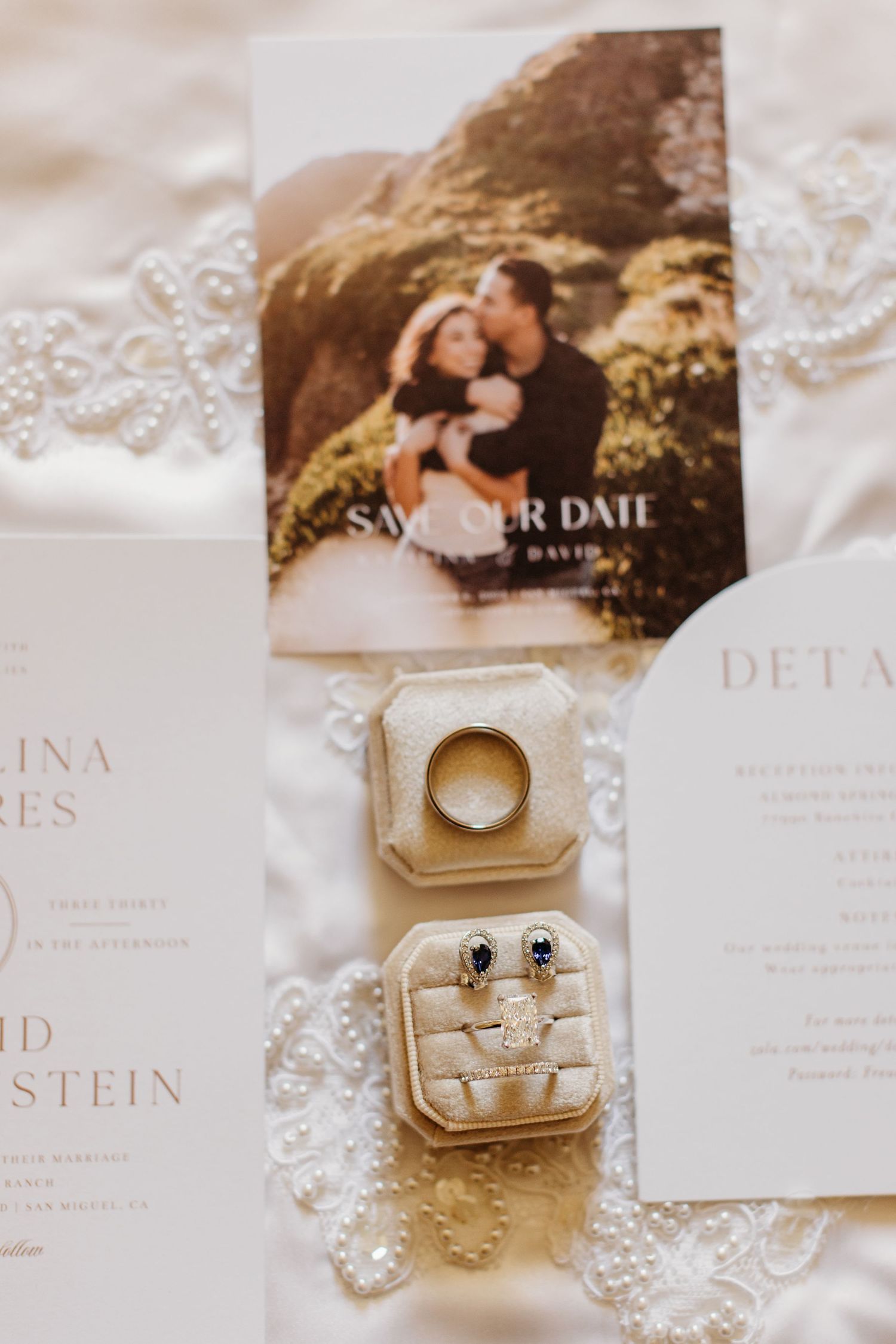 Wedding invitation save the date card with gold ring box and jewelry details on delicate lace background.
