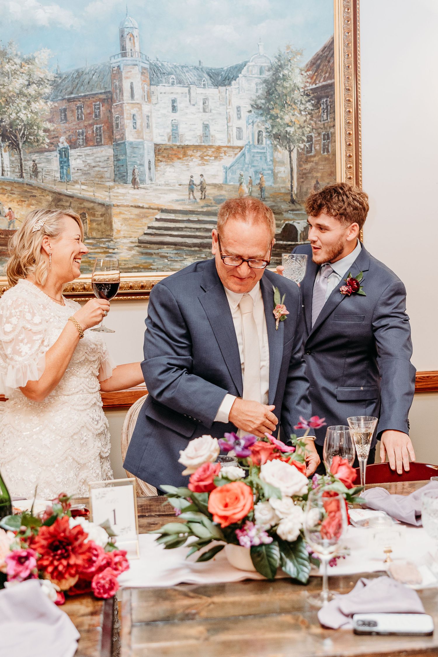 Wedding reception table with pink floral arrangements and vintage artwork on the wall.
