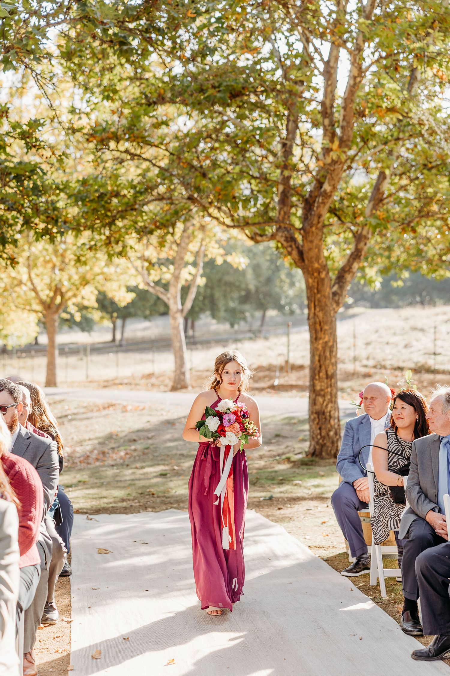 Wedding party members sharing emotional moments and hugs in a sunlit outdoor setting.