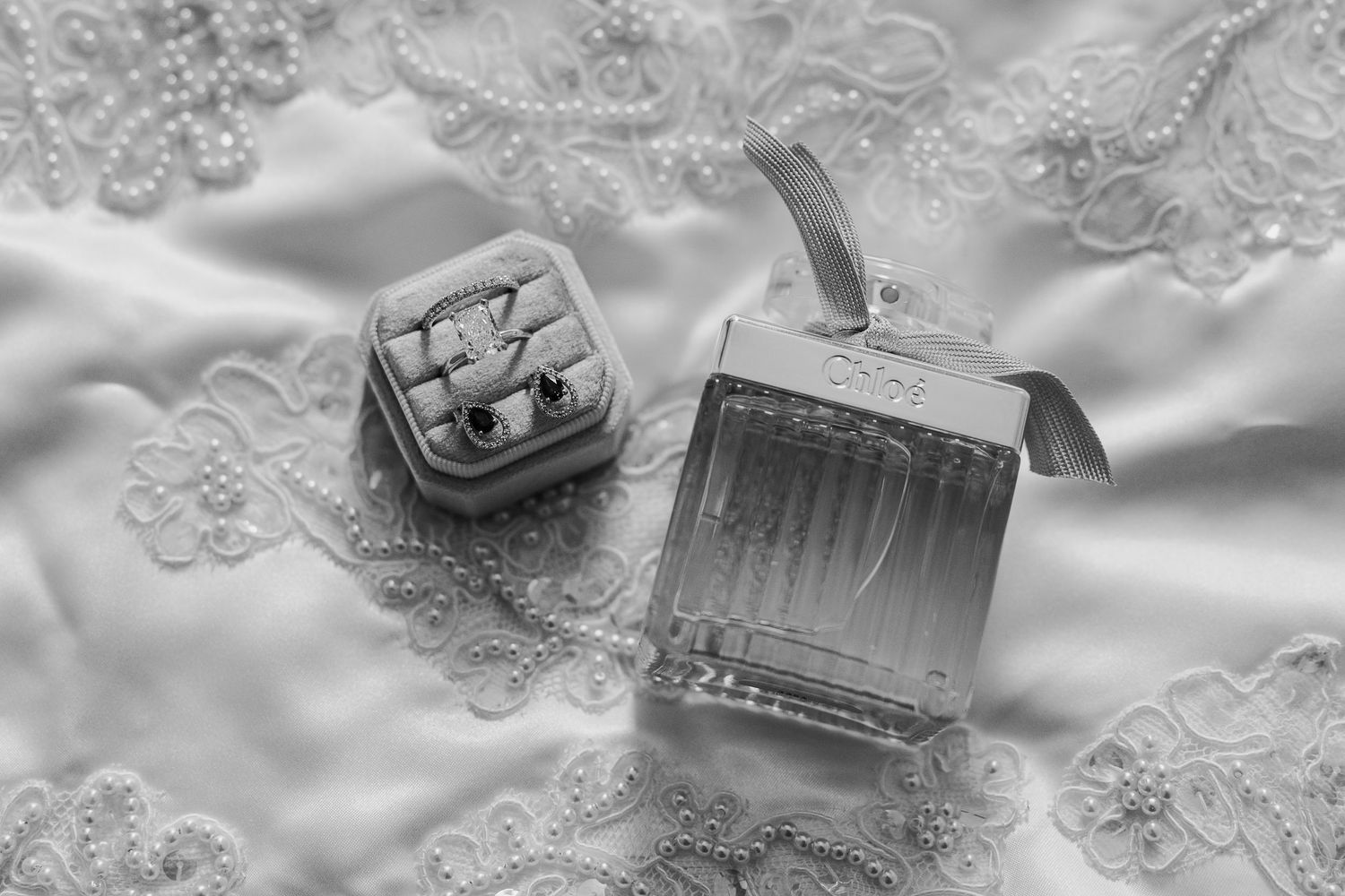 Vintage style black and white photo of antique sewing items including thread, scissors and lace on white fabric.