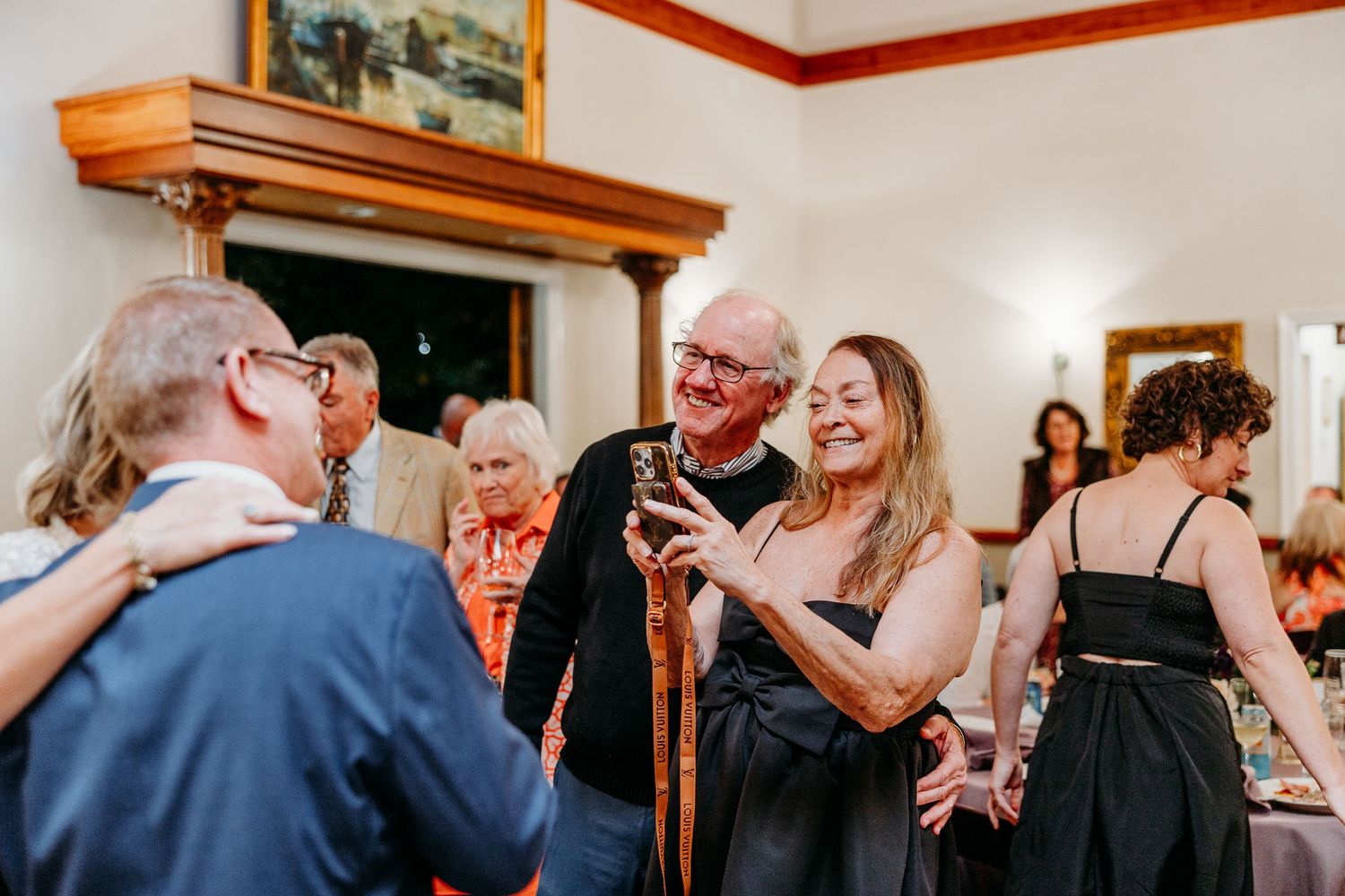 A group of guests dance and celebrate at an indoor reception party.