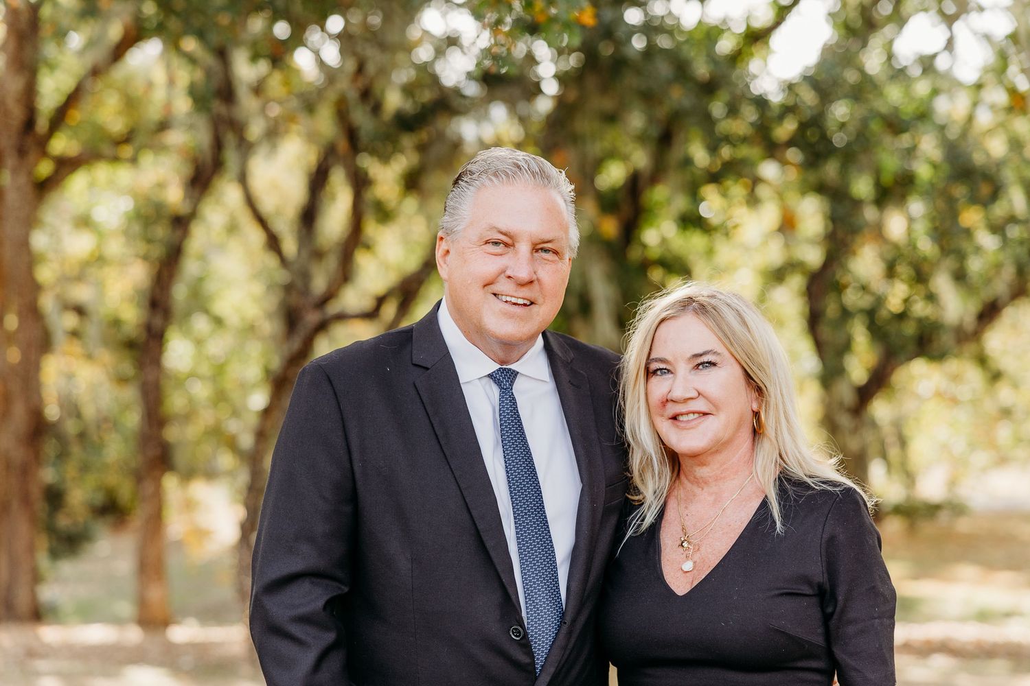 Wedding celebration captured in natural outdoor setting with autumn trees.