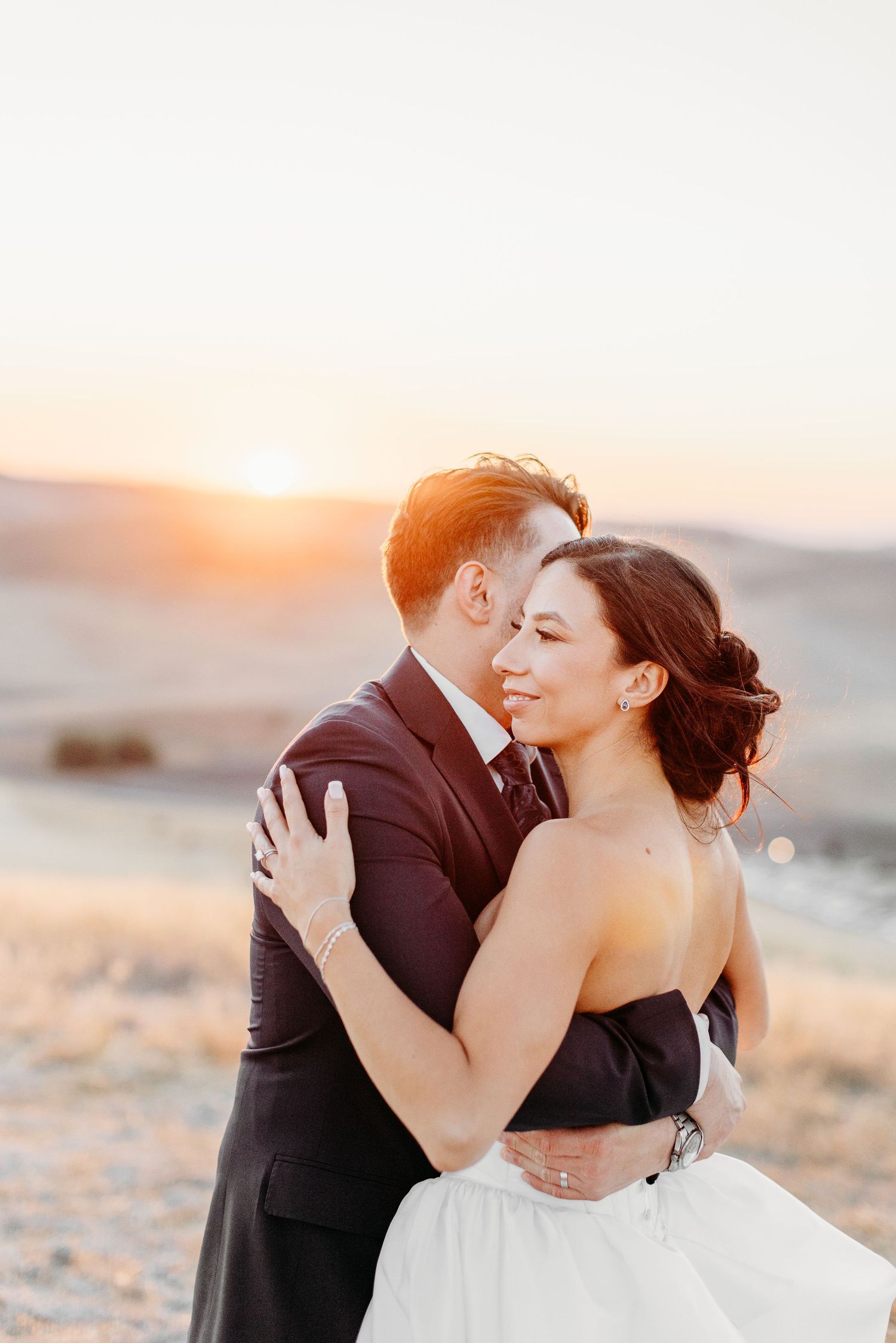 A romantic sunset photoshoot on rolling hills with a couple in formal wedding attire.