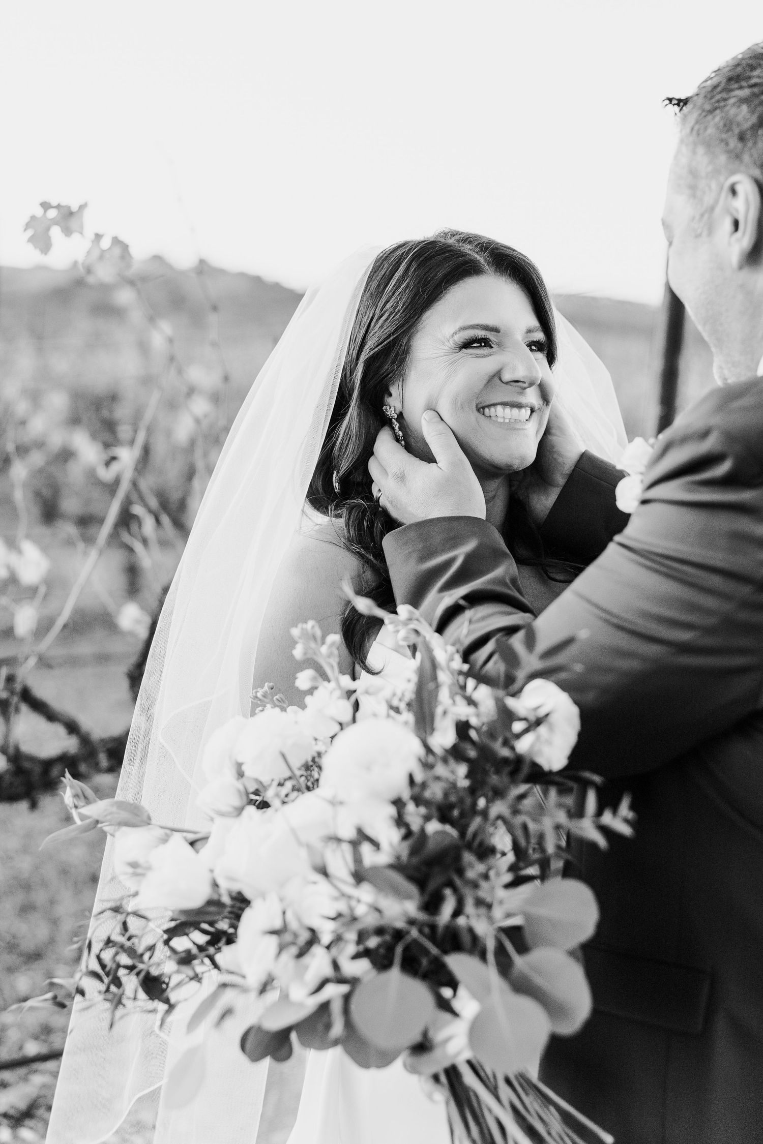 Romantic black and white wedding portraits capture intimate moments between newlyweds with floral bouquet.