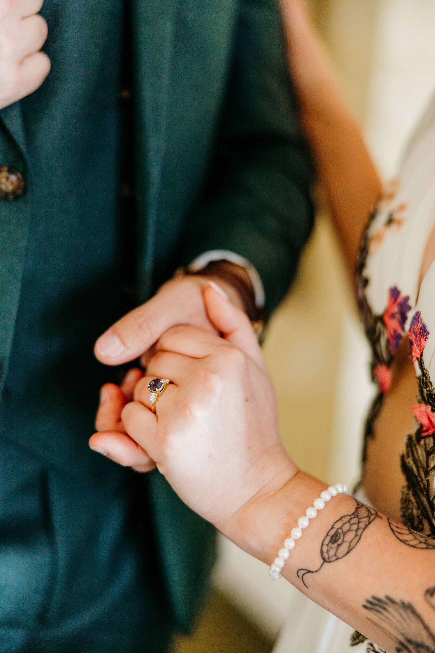 Close-up of hands wearing delicate pearl bracelets with visible tattoo artwork.