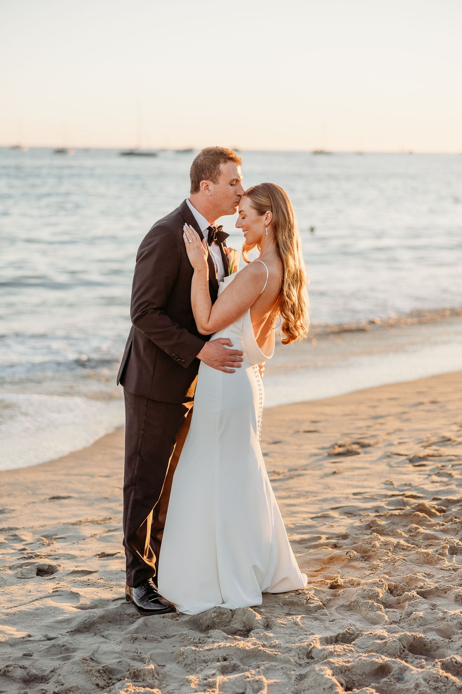 Romantic sunset beach wedding portrait with ocean backdrop and golden light.