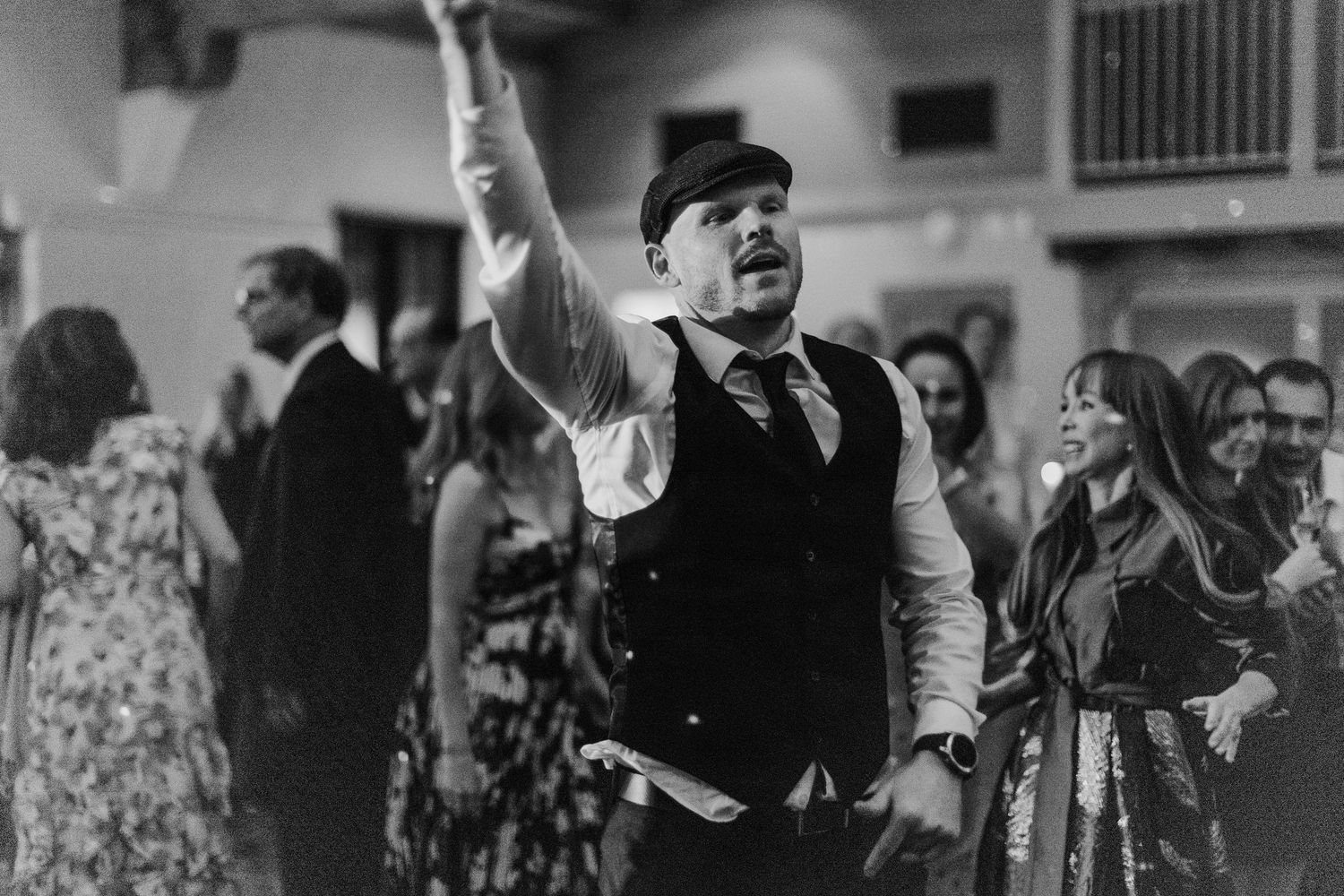Black and white photo of wedding reception guests dancing and celebrating.