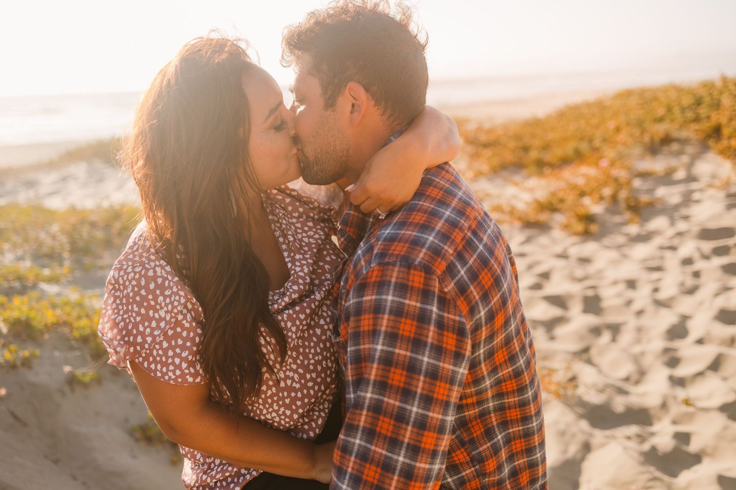 Sunset beach portrait of couple in close embrace with warm golden lighting.