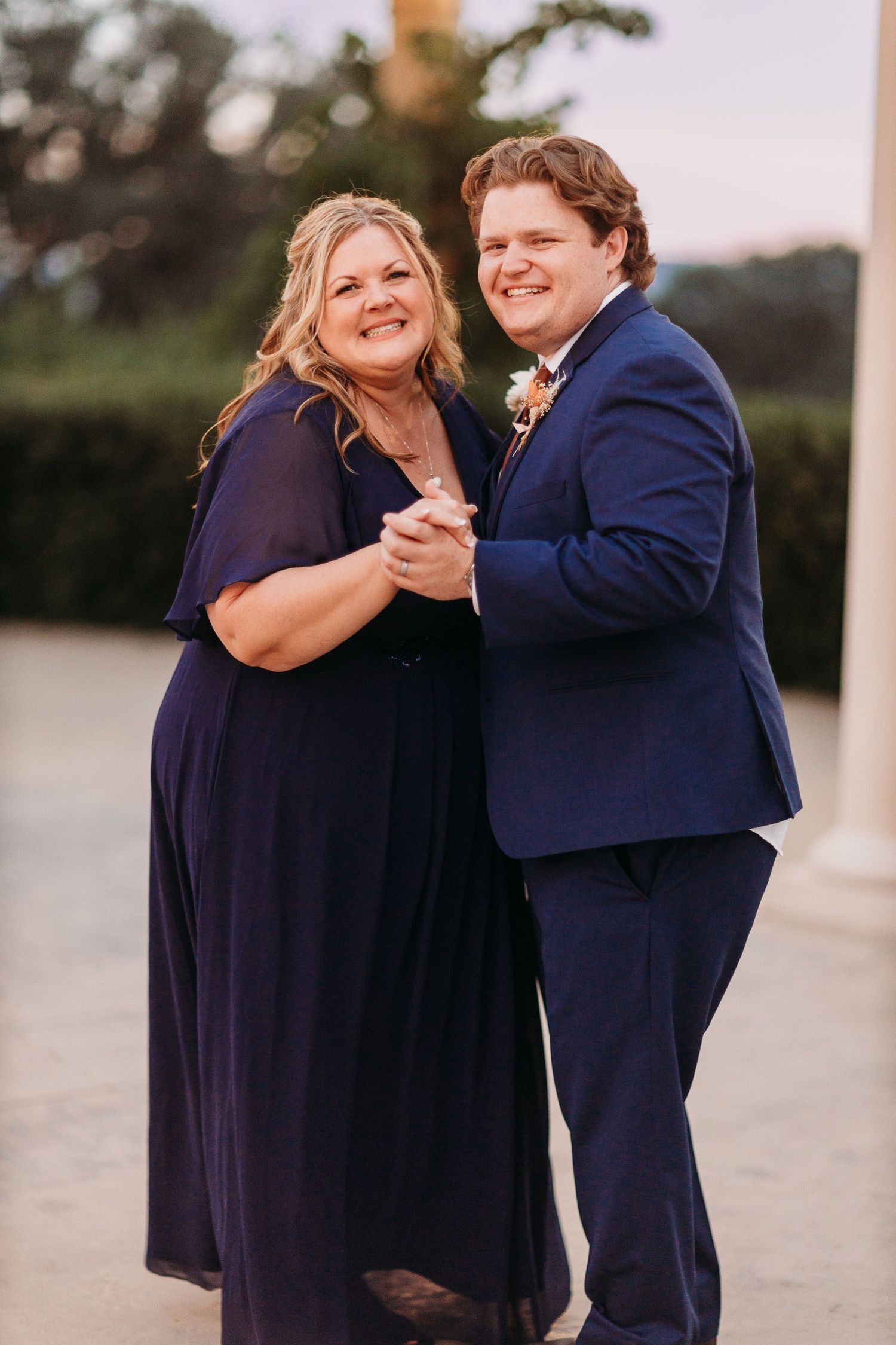 A happy couple in coordinating navy attire share a romantic dance moment.