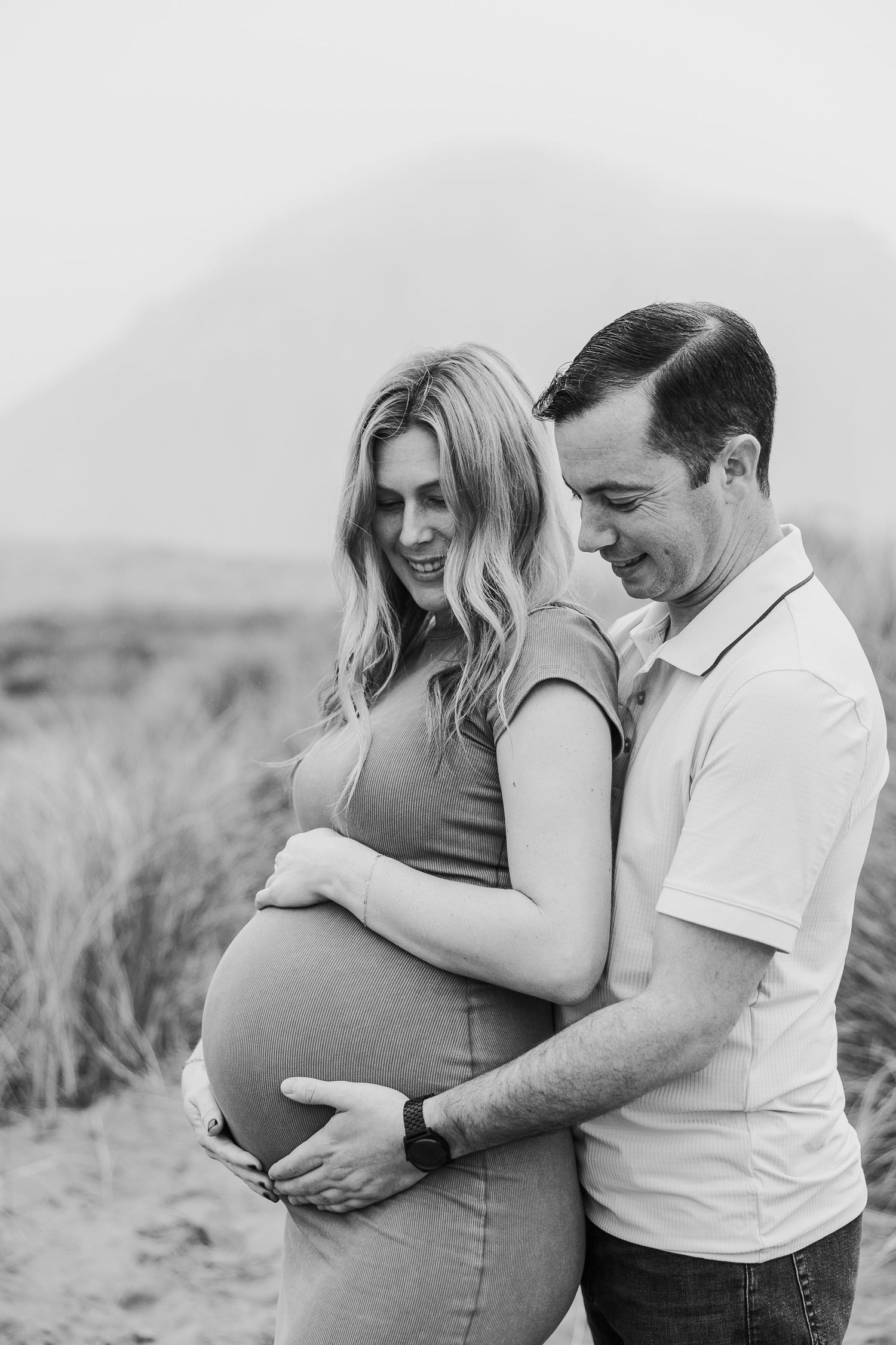 Black and white maternity photo of couple sharing loving moment in nature.