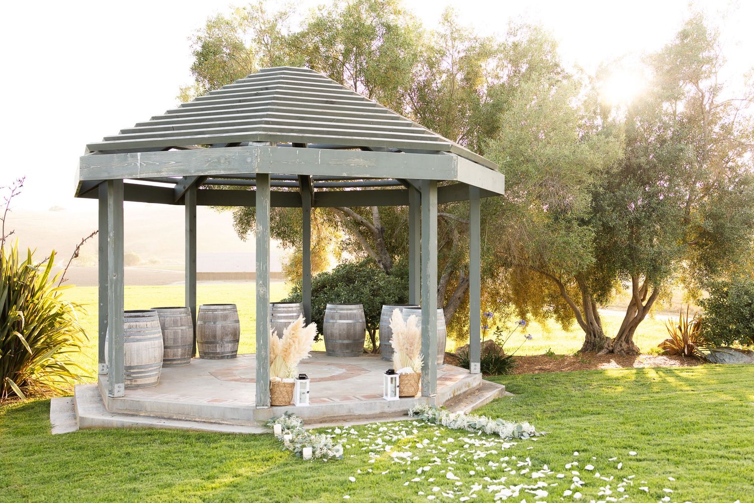 A serene gazebo setup with lanterns and decorations at sunset against rolling hills.