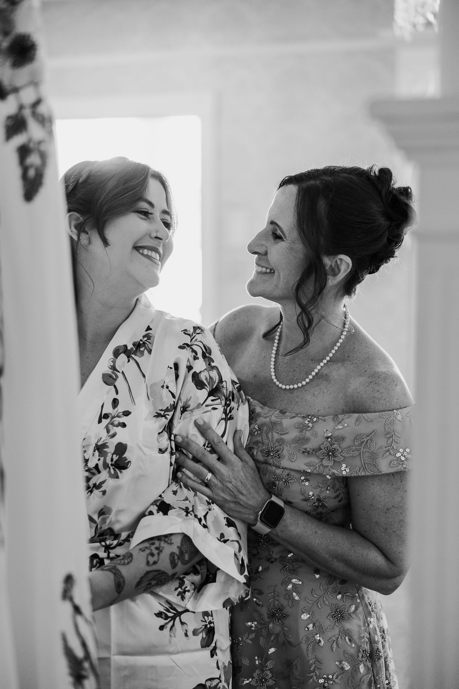 Black and white candid photos show two people sharing joyful laughter in a wedding setting.