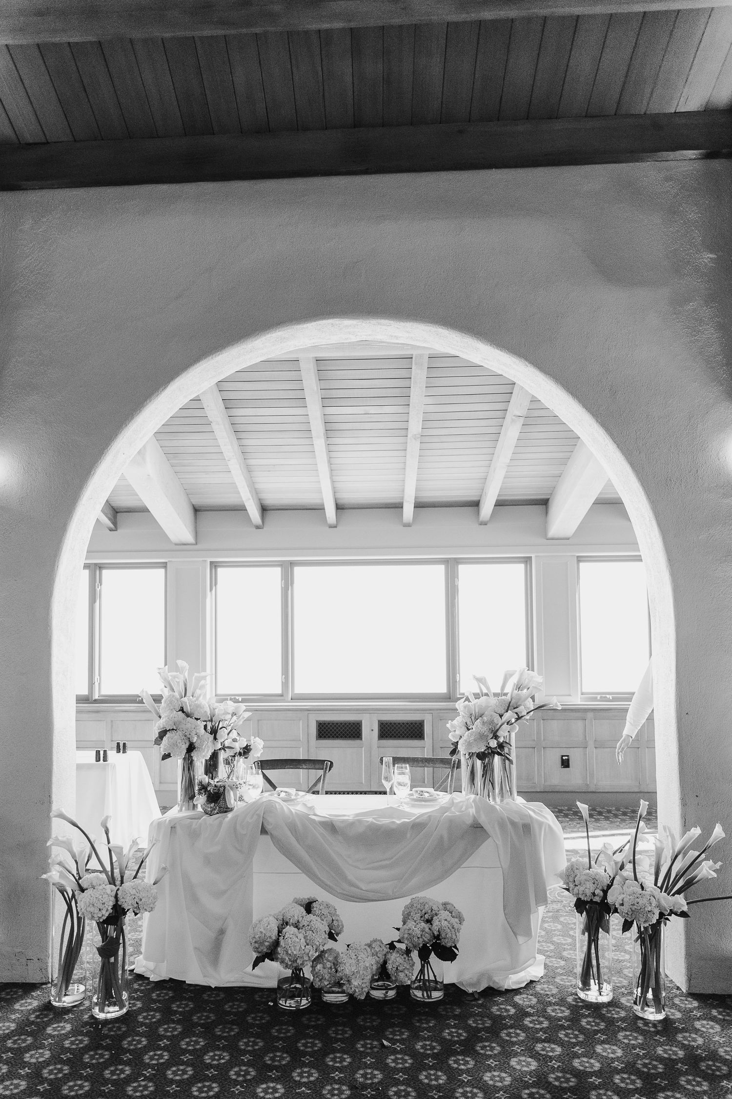 Wedding reception venue with white tablecloths and arched architectural details in black and white.