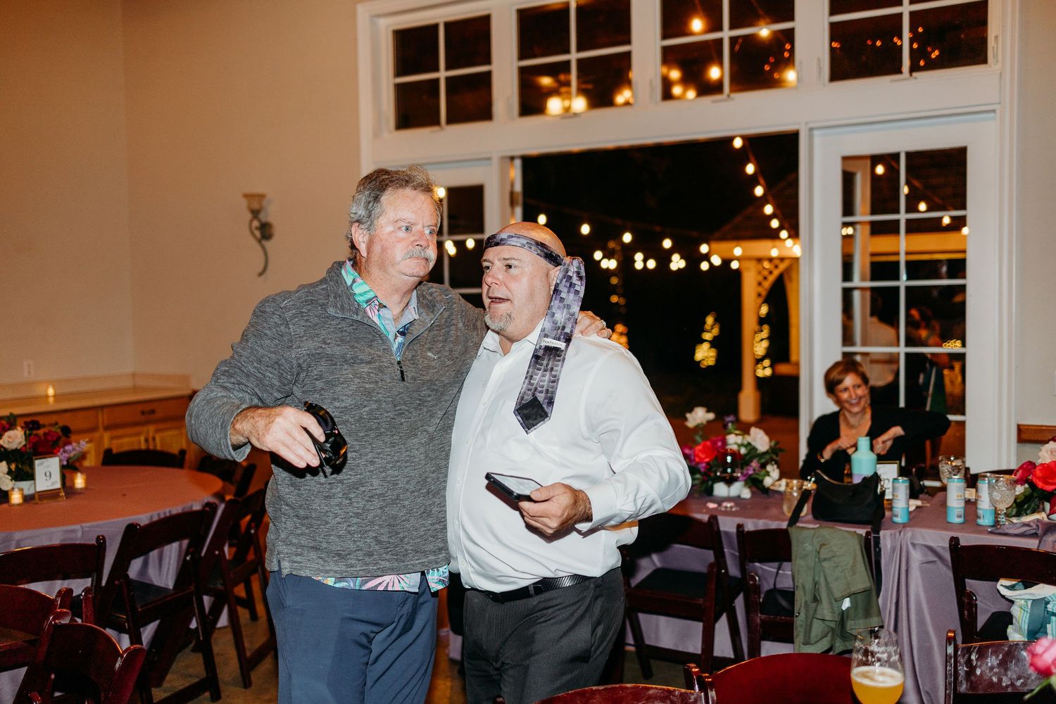 Evening wedding reception with string lights and large windows creating ambient atmosphere.
