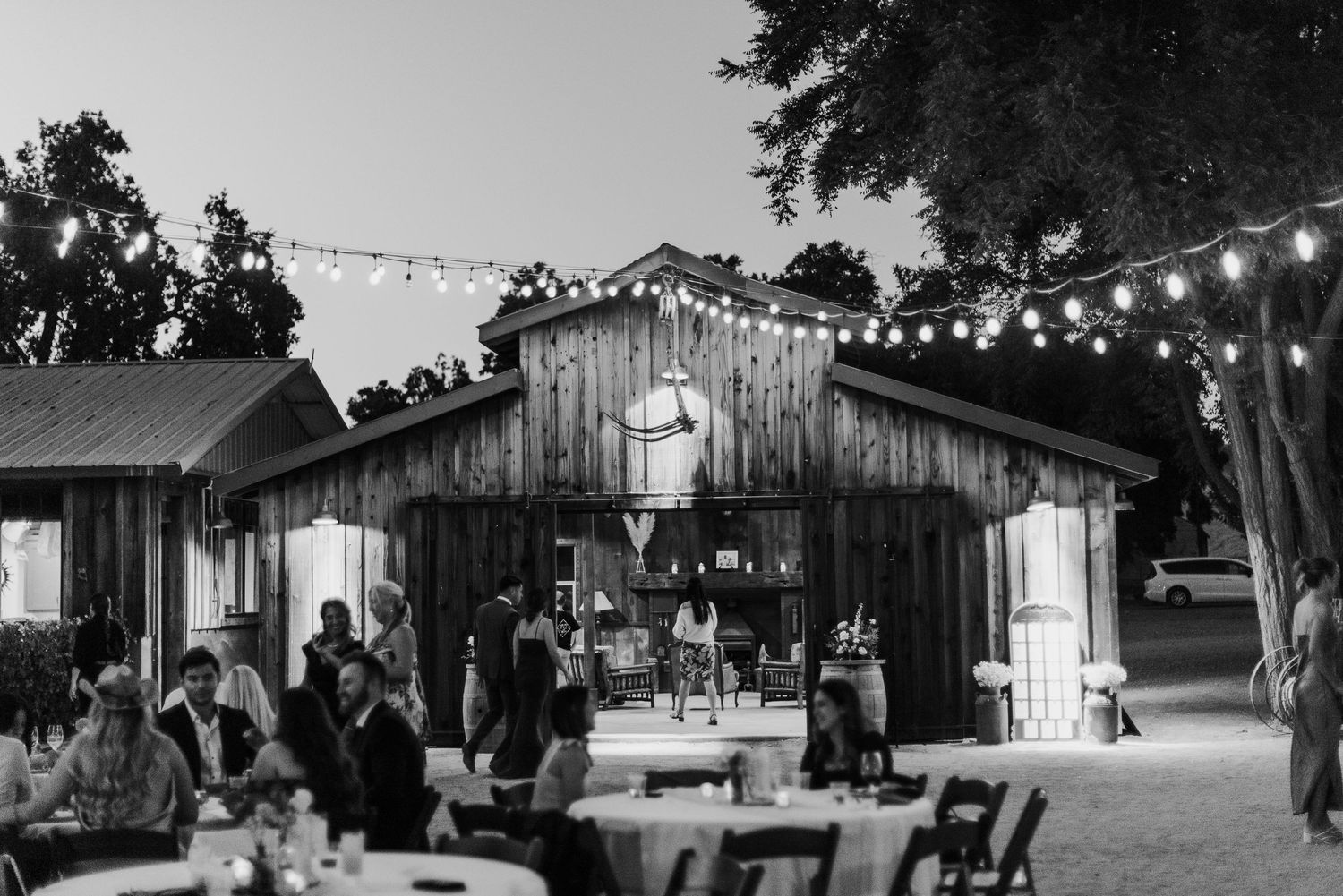 Rustic barn wedding venue at night illuminated by string lights creating romantic ambiance.