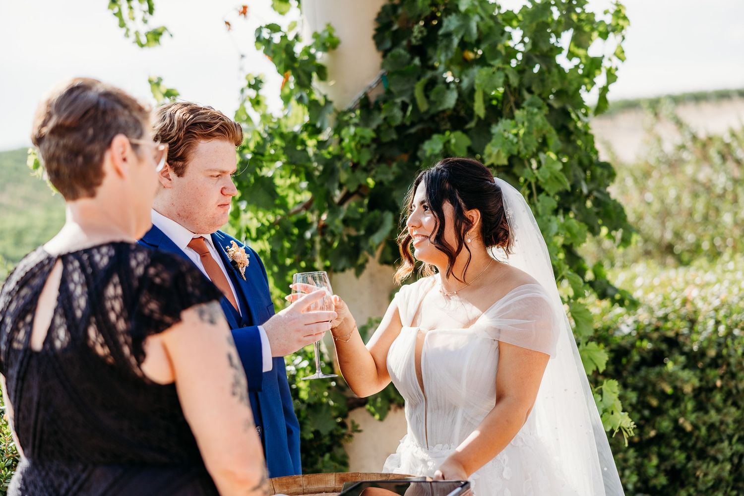 Couple participates in intimate wine ceremony during outdoor vineyard wedding.