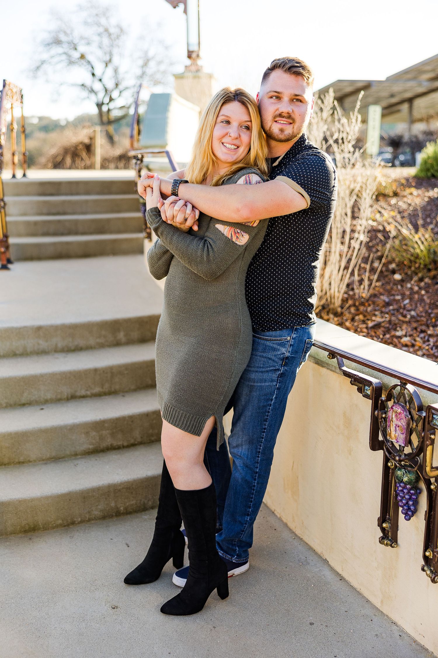 Sweet couple posing together on stone steps with decorative railings.