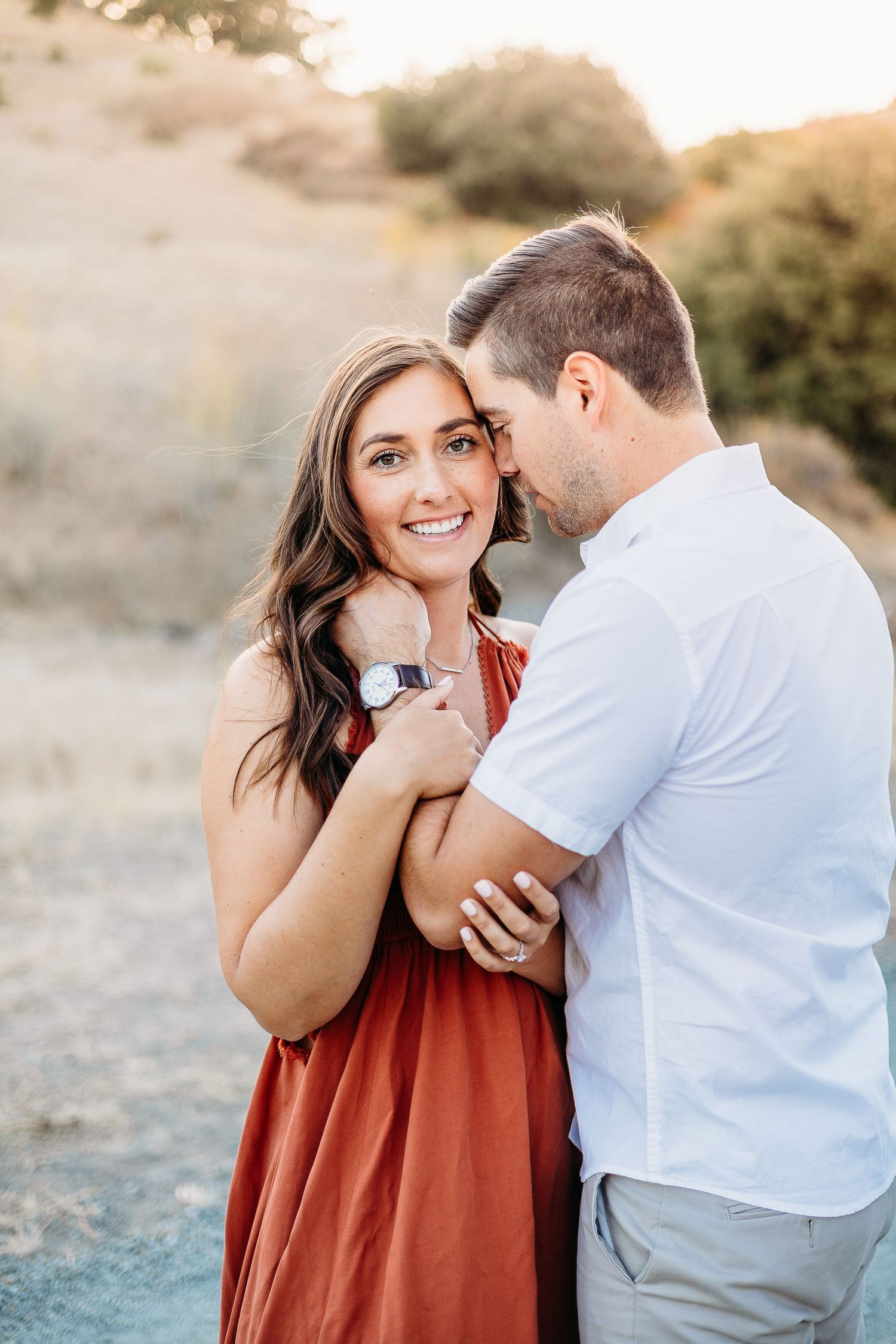 Intimate portrait of couple in coordinated outfits against golden hills backdrop.