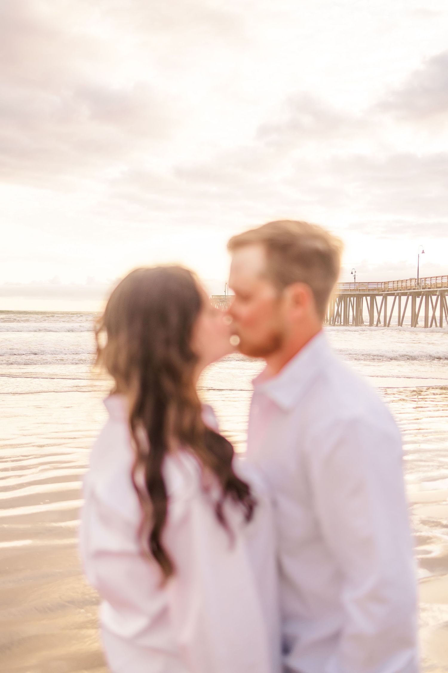 Romantic seaside moment at sunset with a pier silhouetted in the background.