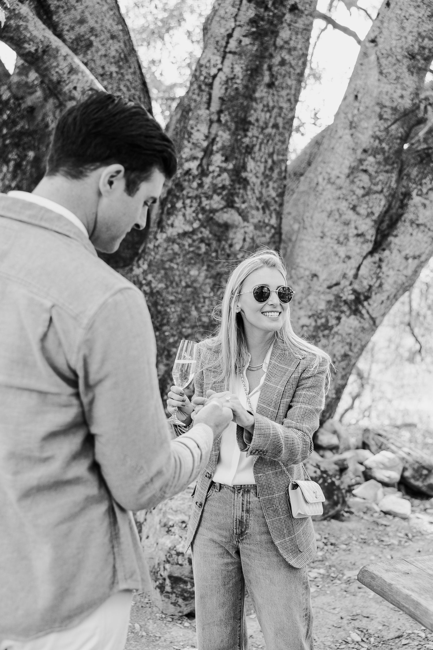 A series of black and white photographs showing a couple in casual attire interacting near trees.