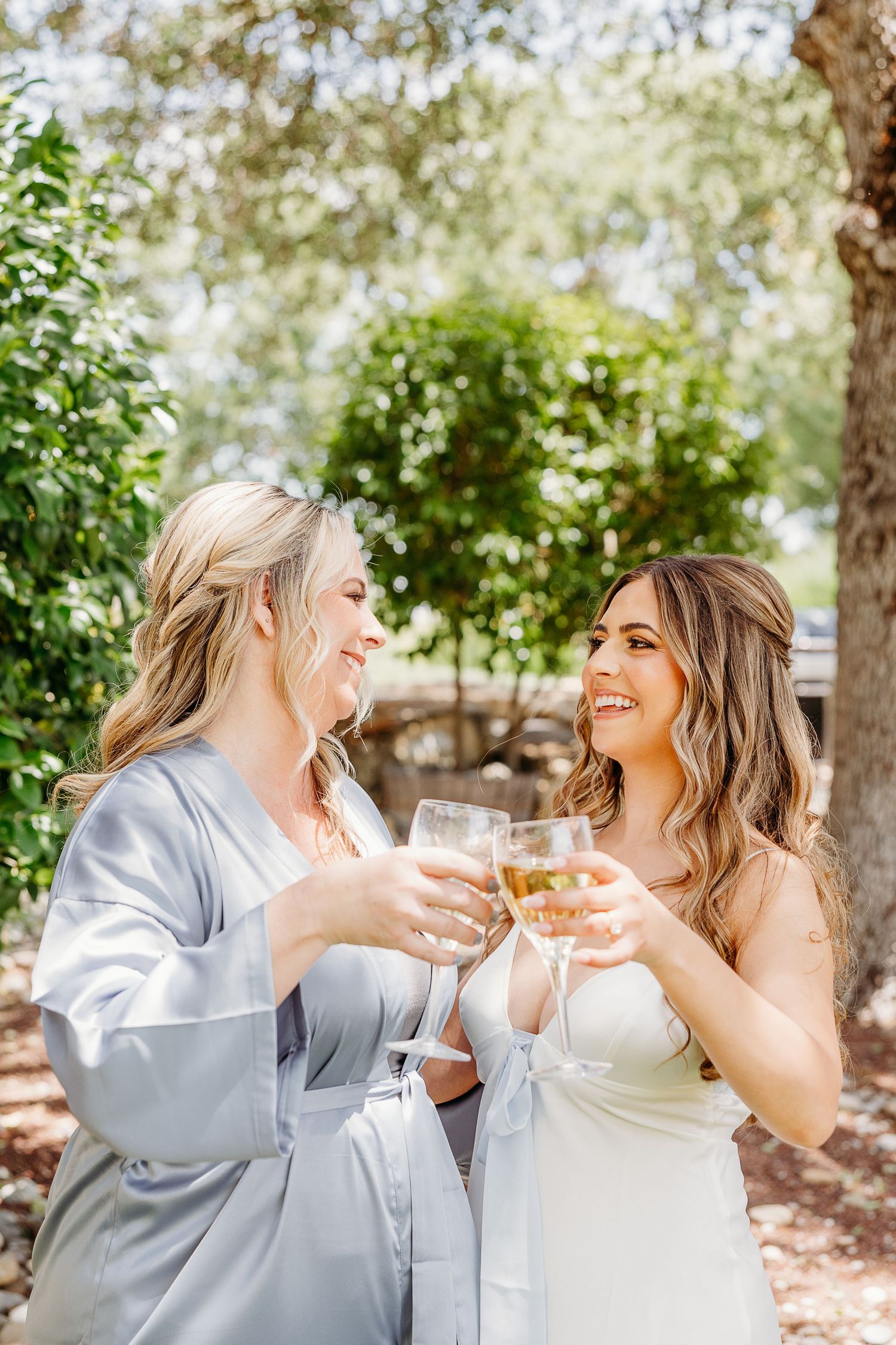 A sun-drenched outdoor scene captures two people in white and grey attire sharing drinks and laughter.