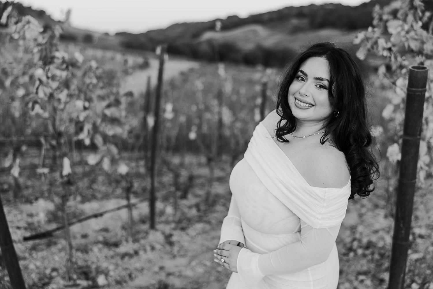 A romantic photoshoot in a vineyard with rustic wooden posts and autumn scenery.