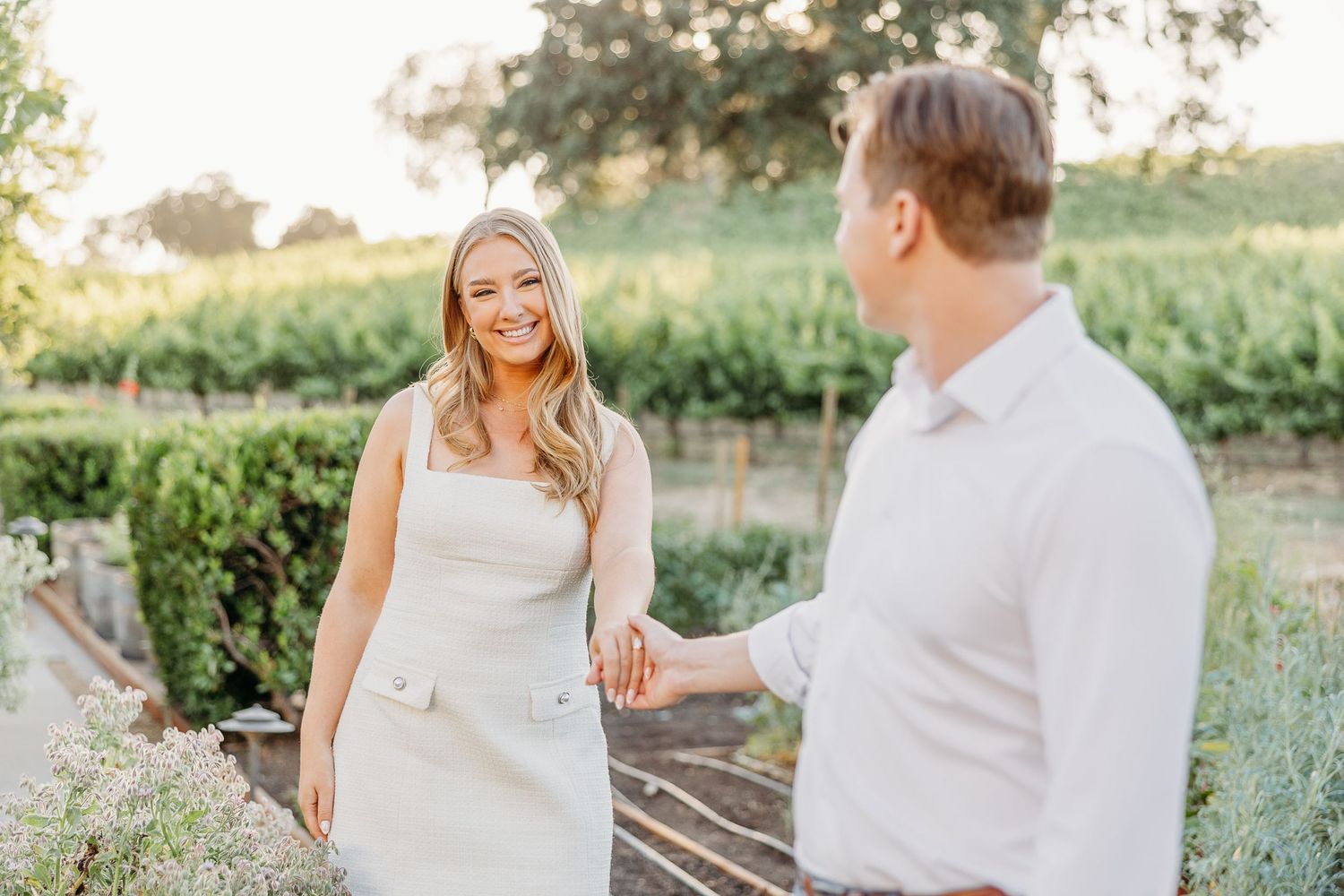 A romantic couple shares tender moments in a sunlit garden setting during a golden hour photo session.
