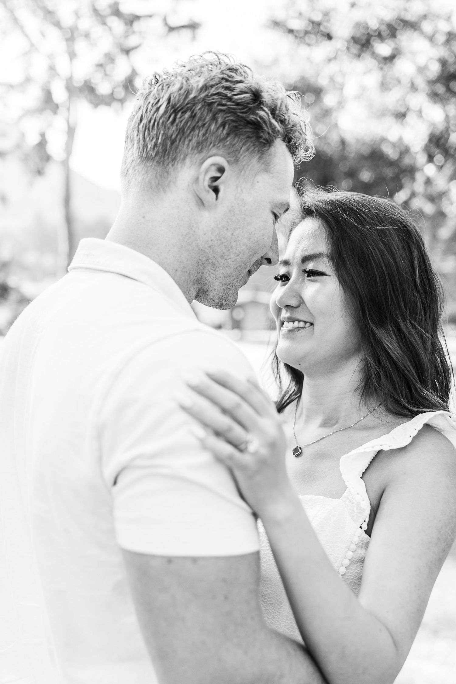 Black and white portrait of couple sharing an intimate moment outdoors.