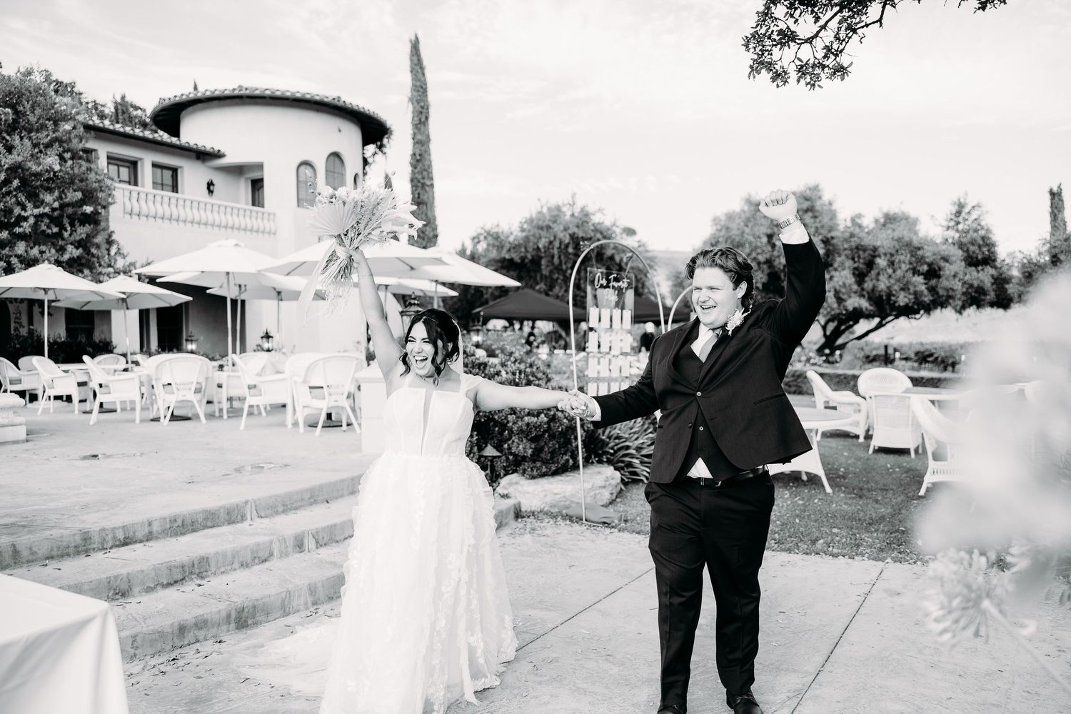 Black and white celebratory moment on stone steps with Mediterranean villa in background.