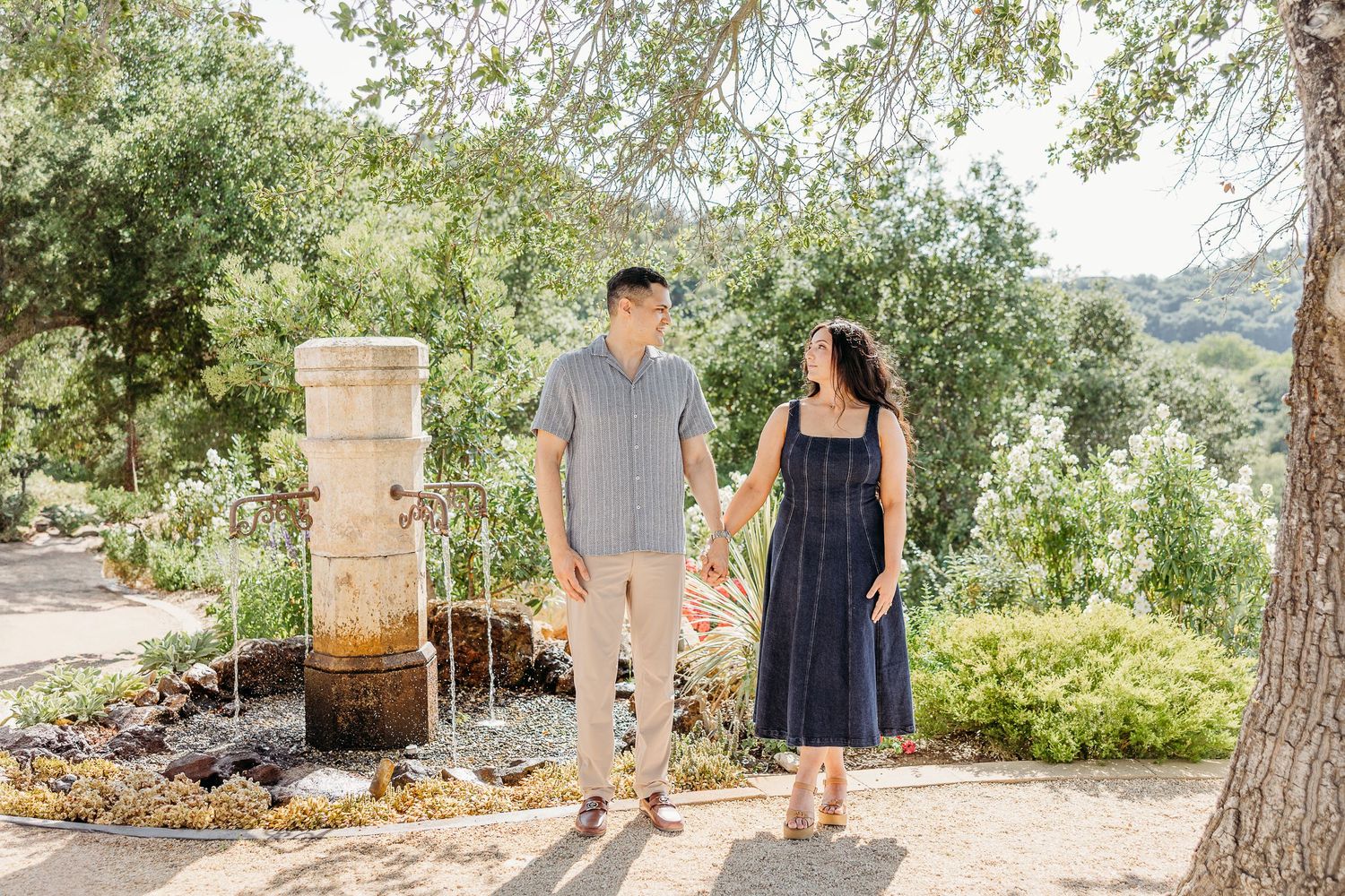 A couple in coordinating outfits walking together in a lush garden setting.