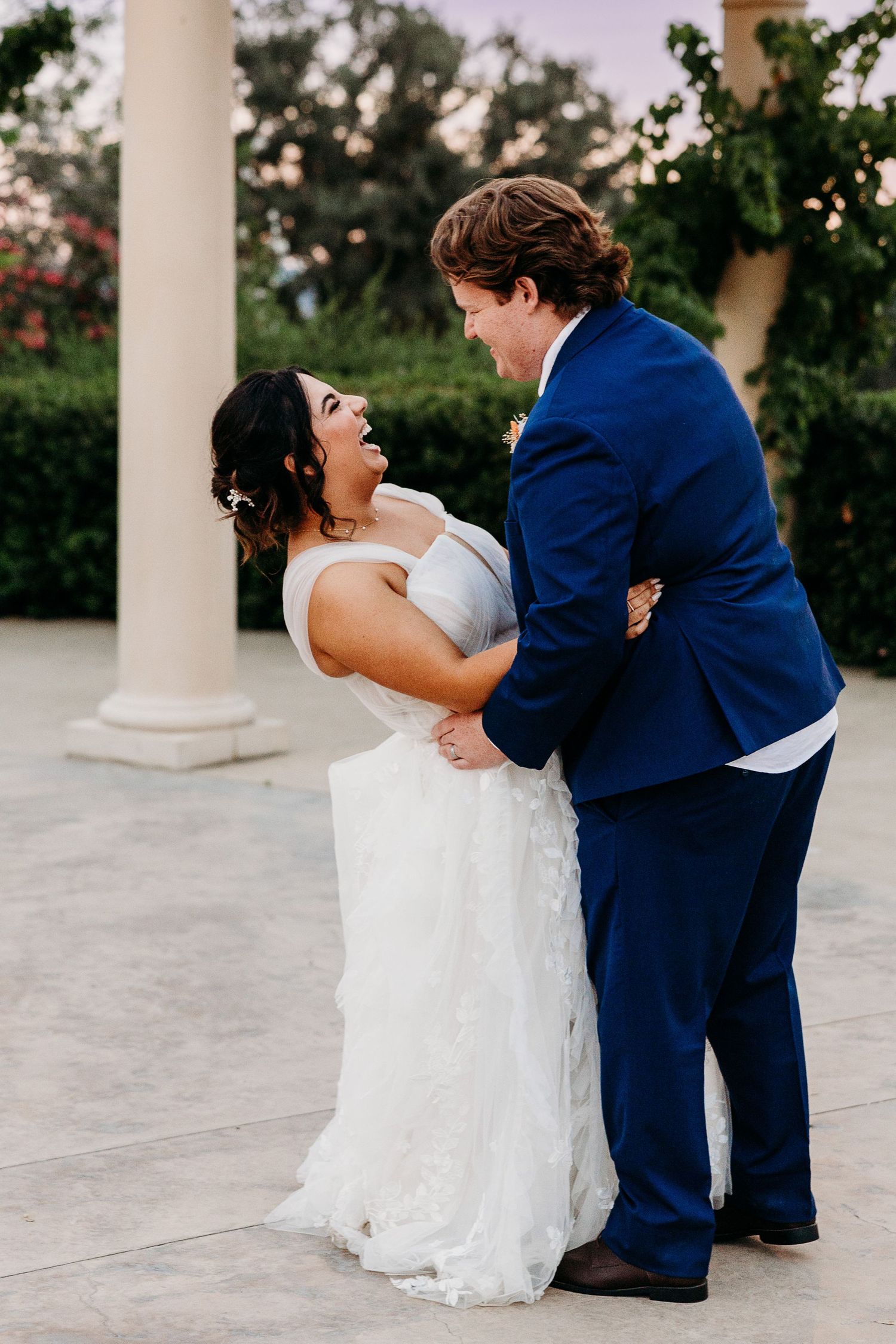 A joyful moment between newlyweds near elegant white columns.