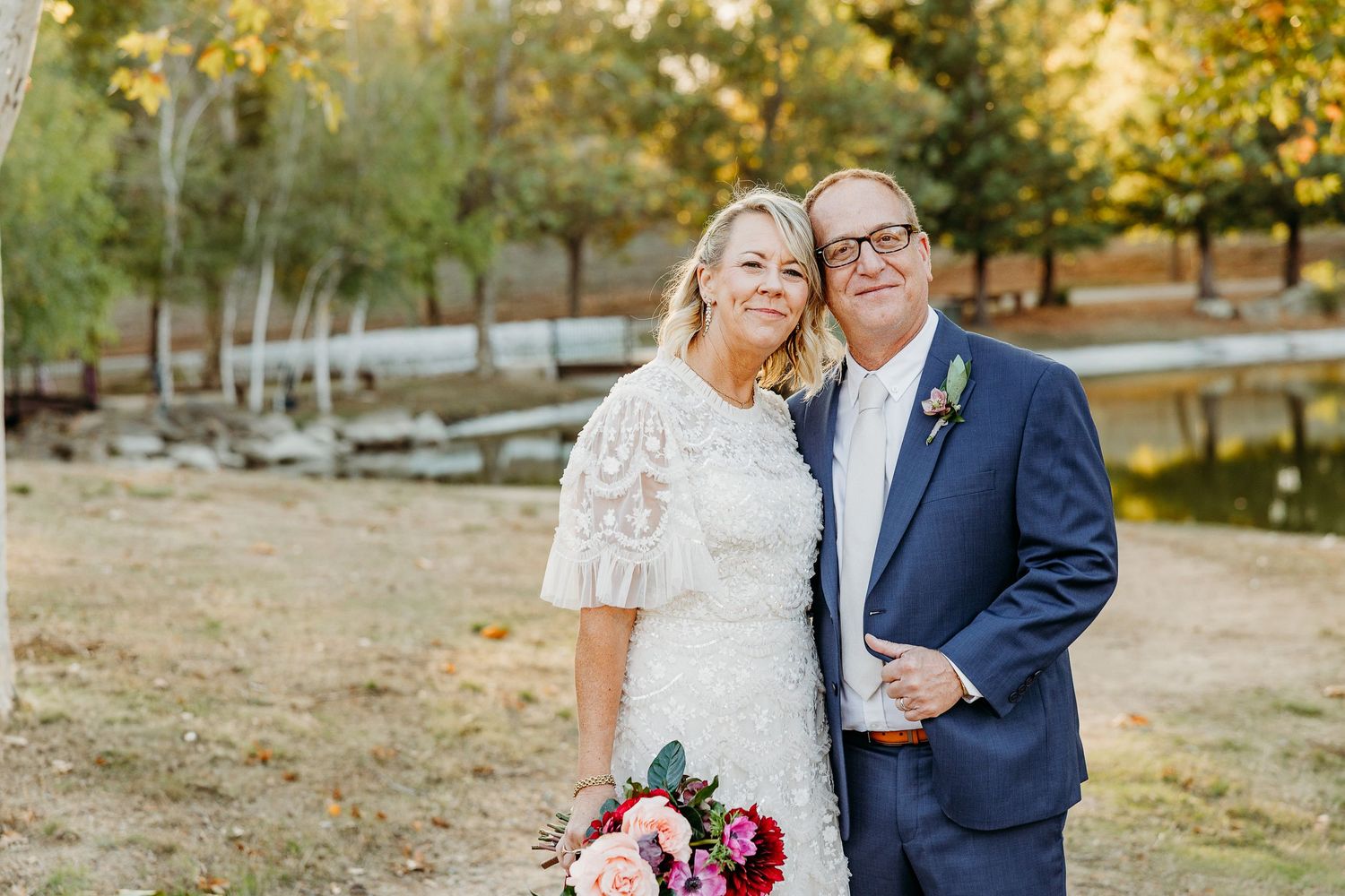 Romantic wedding portraits captured in a scenic outdoor setting with autumn foliage.
