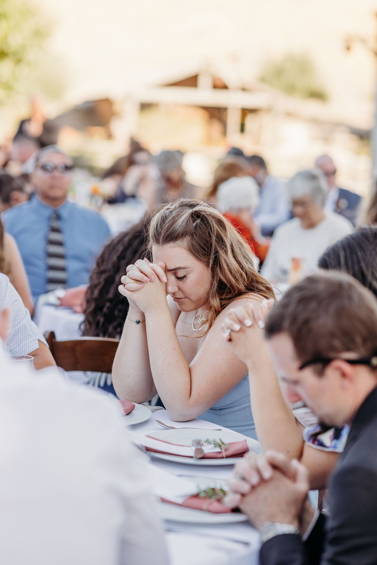 Wedding reception guests enjoying dinner at outdoor tables with white linens.