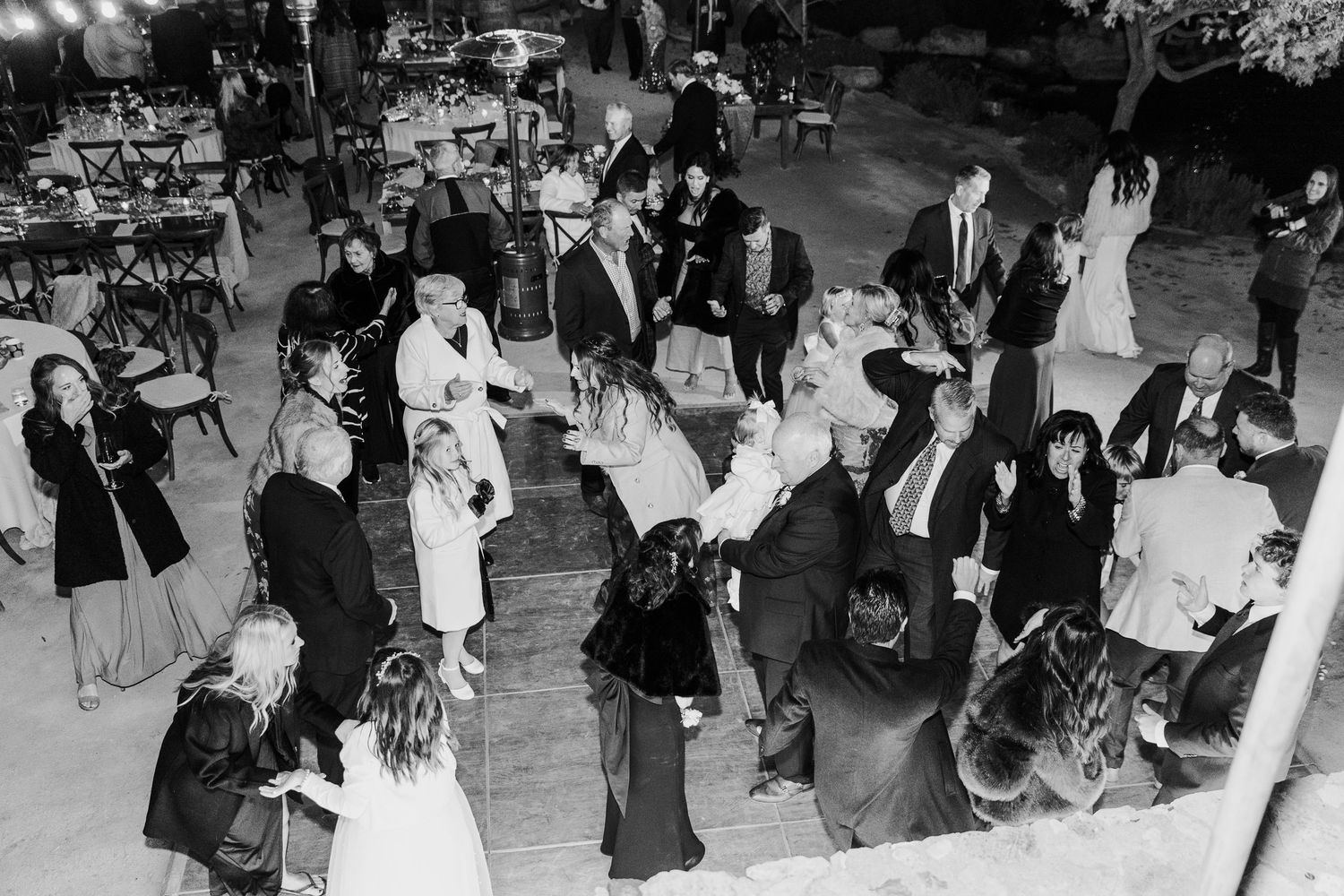 Aerial view of wedding guests dancing on a crowded dance floor at night.