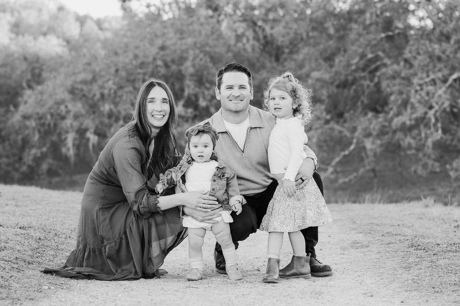 Black and white family portrait series showing intimate moments and interactions in an outdoor setting.