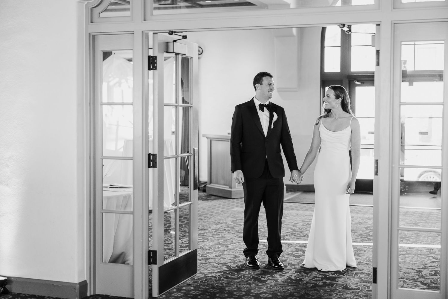 Wedding couple walking and embracing in an elegant bright indoor hallway.