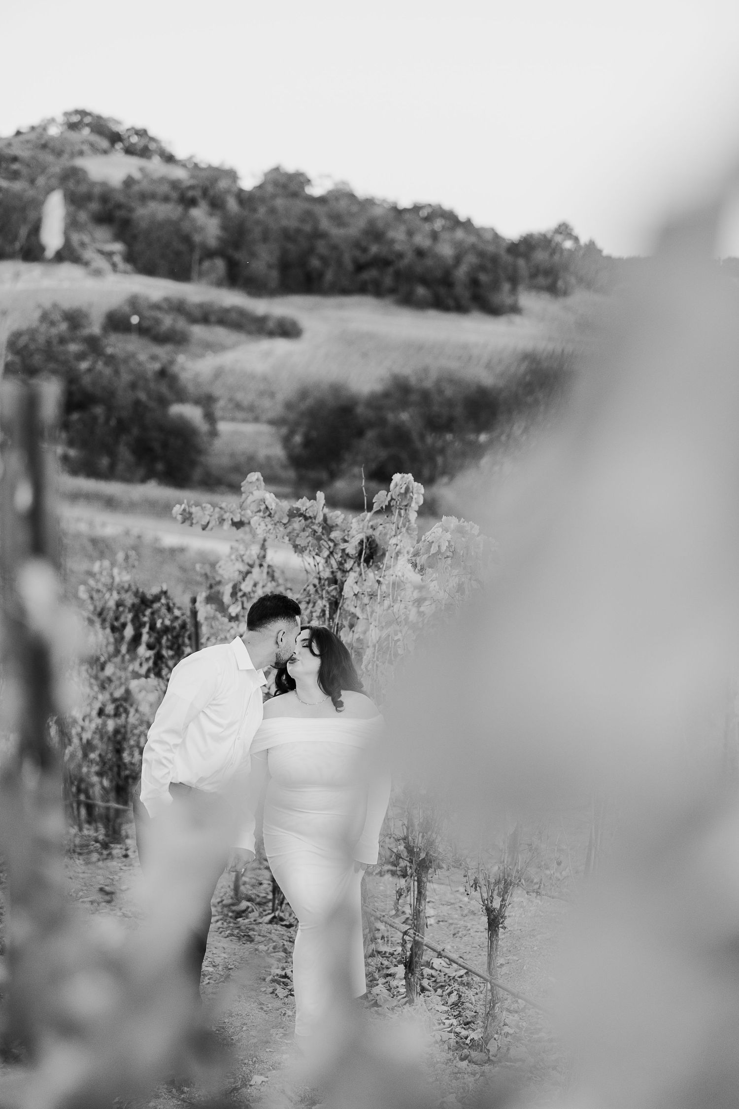 A romantic black and white moment captured in a scenic vineyard setting.