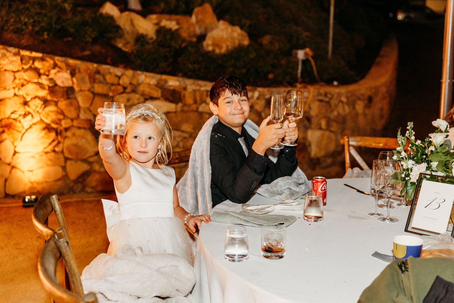 Intimate indoor wedding reception with stone walls and warm lighting illuminating dining tables and place settings.