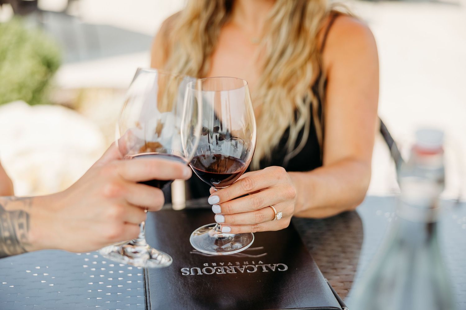Two wine glasses clink together during romantic wine tasting.