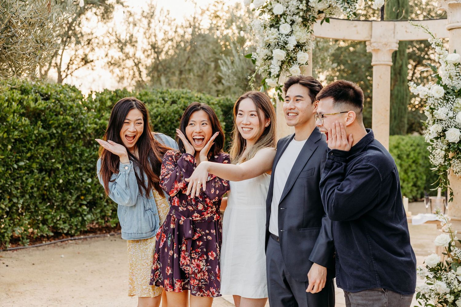 A group of friends laughing and embracing outdoors during a joyful photoshoot session at sunset.
