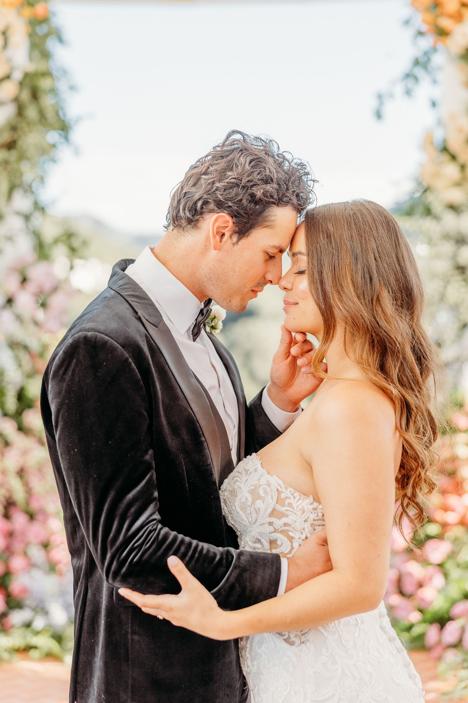Romantic couple sharing intimate moments in a garden setting with blooming flowers in the background.