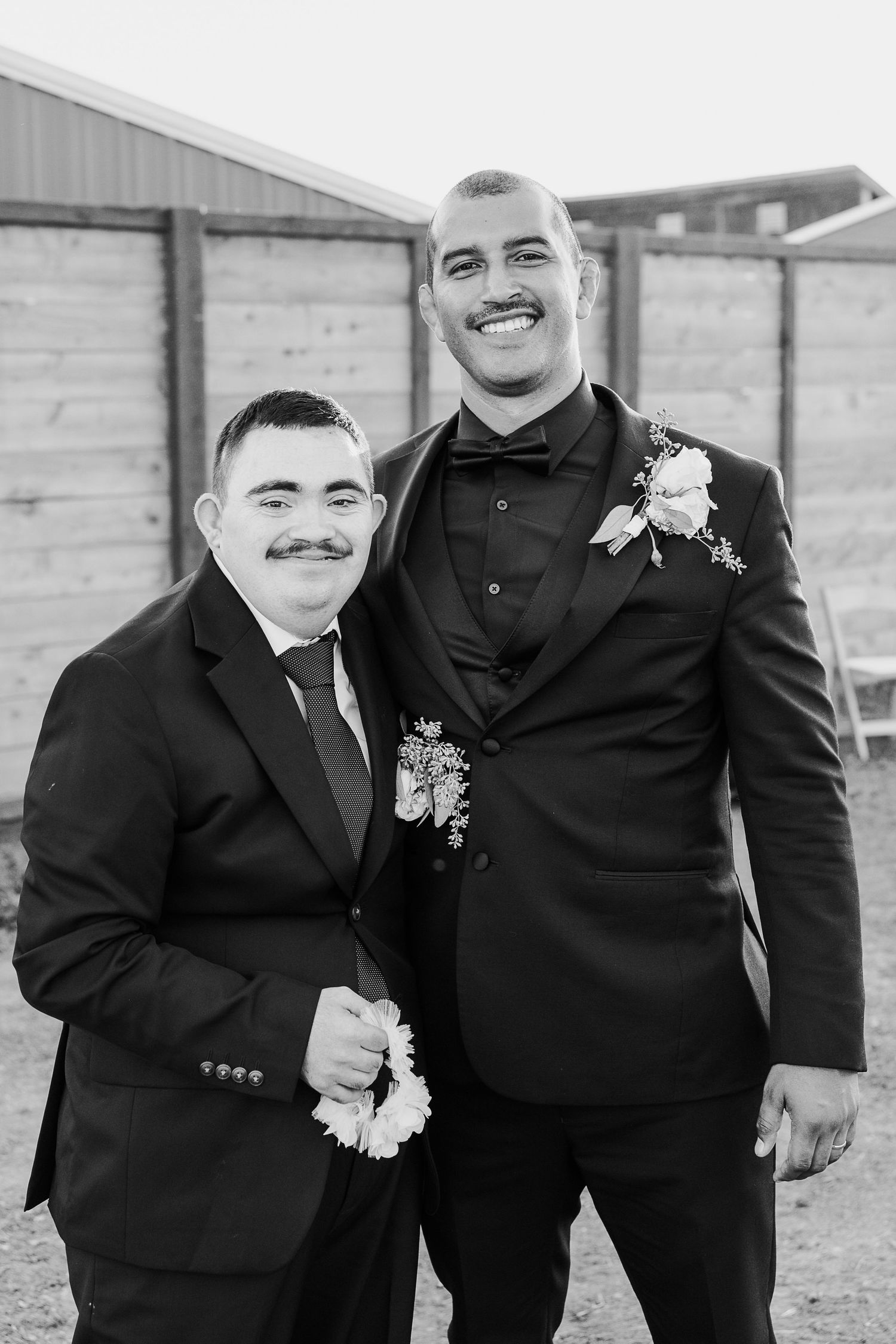 Groomsmen in black suits sharing laughs during wedding photo session.