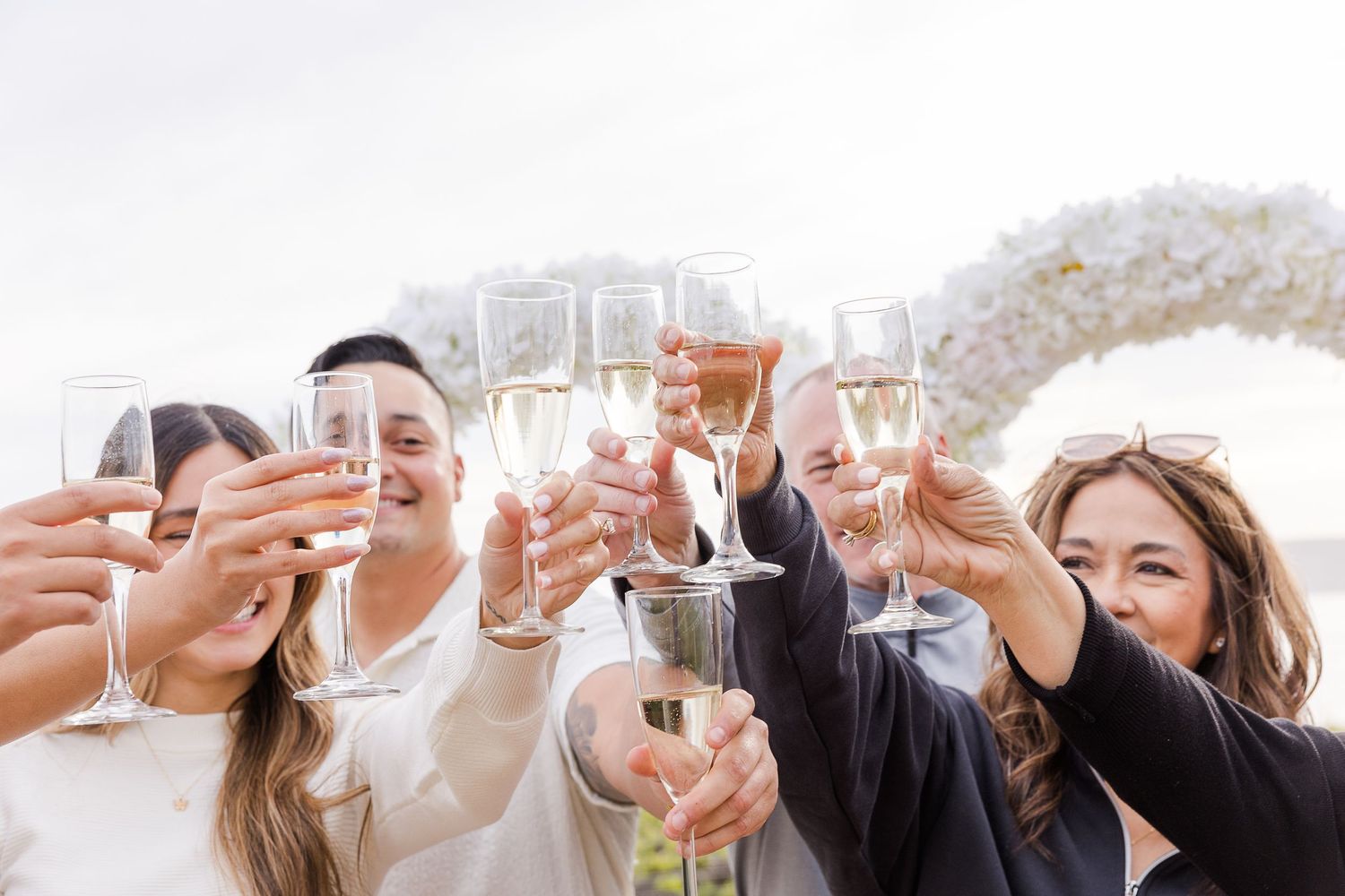 A group of people raise champagne glasses in a celebratory toast at a festive gathering.