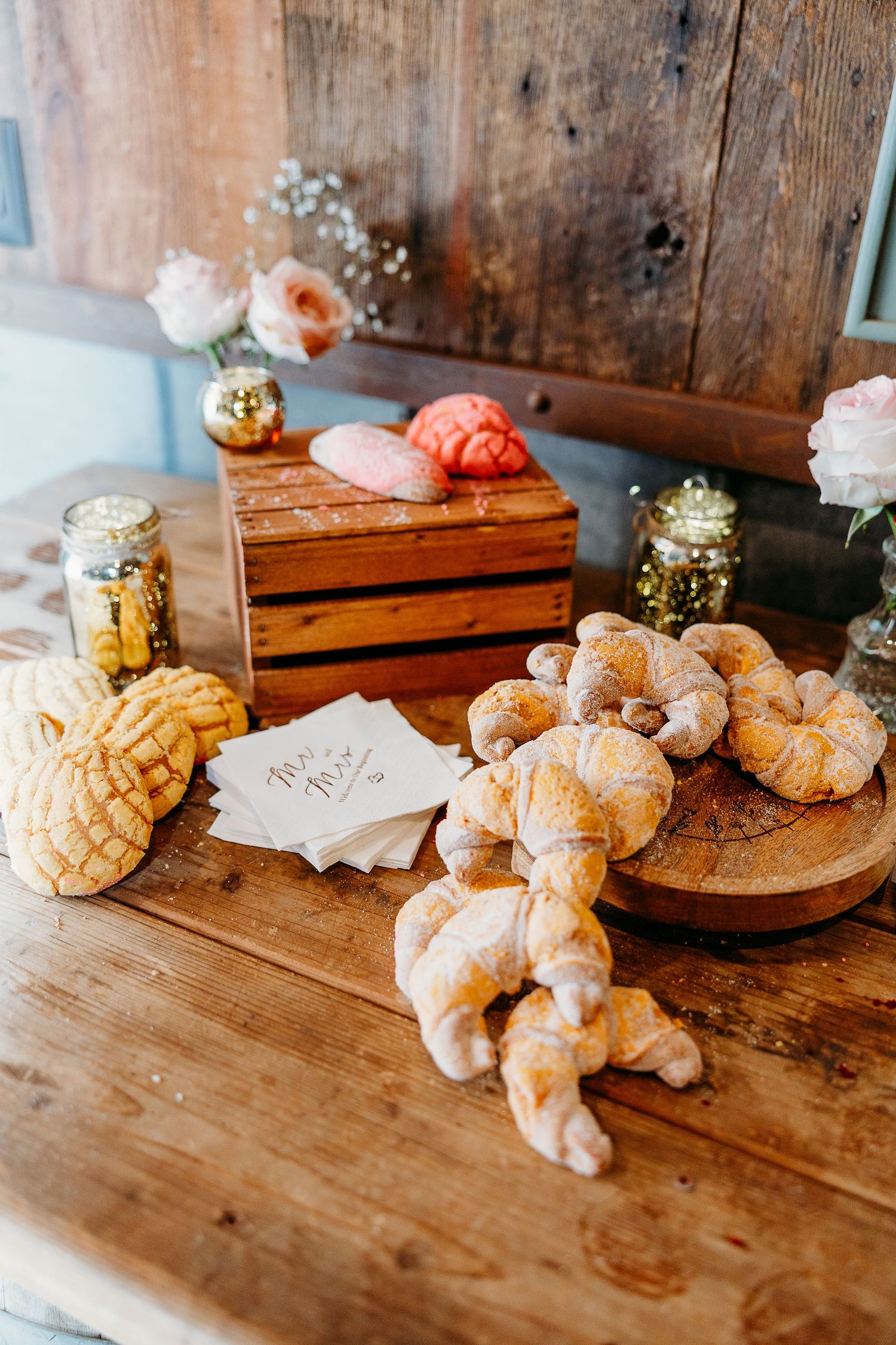 Fresh baked croissants and pastries displayed on a rustic wooden table.