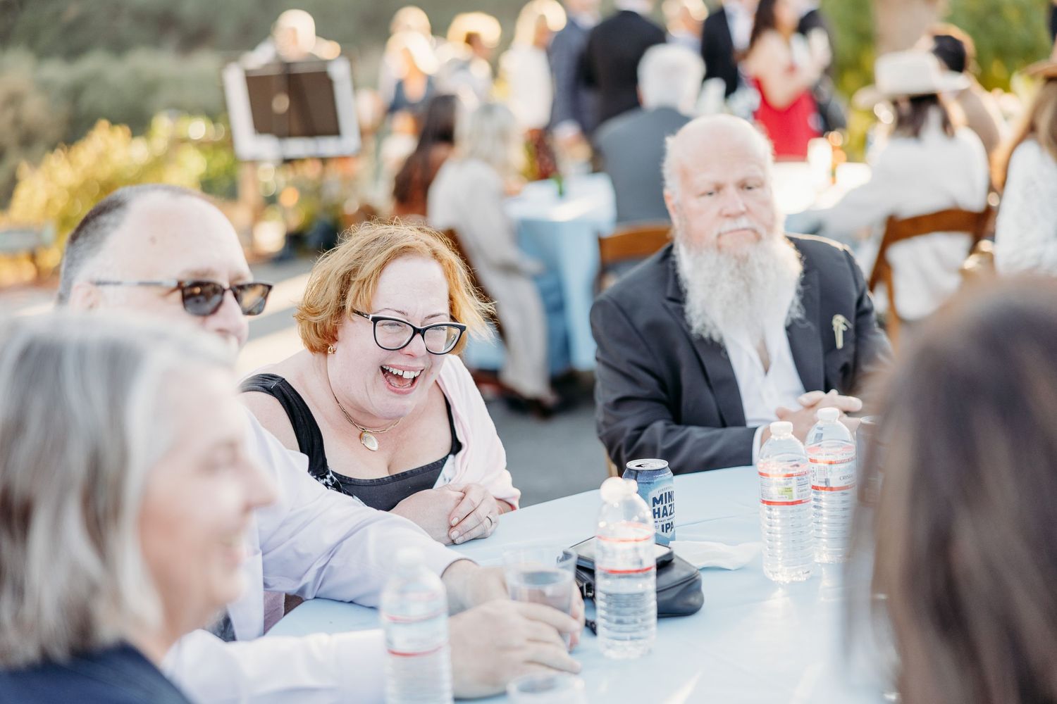 Guests gather at outdoor tables for a celebratory event on a sunny afternoon.